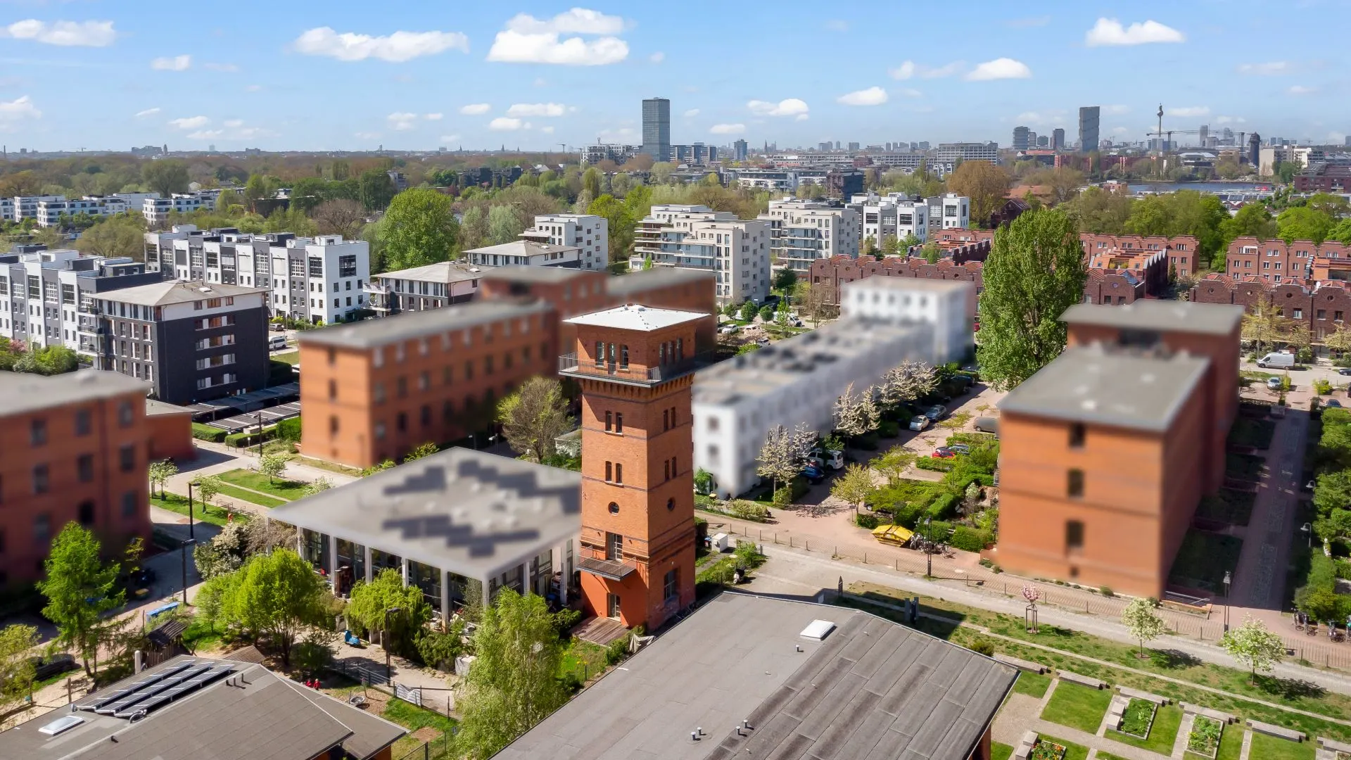 Blick auf Wohngebäude mit rotem Turm in einer modernen Wohnsiedlung bei Tag.