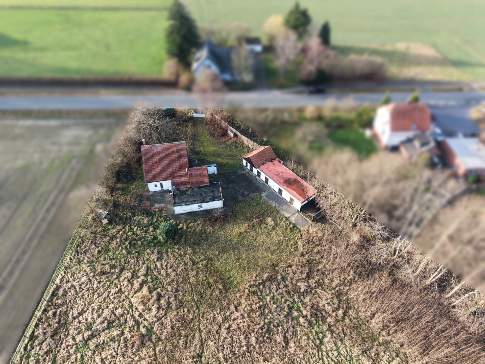 Luftaufnahme eines Hauses mit Nebengebäude auf großem, bewachsenem Grundstück.