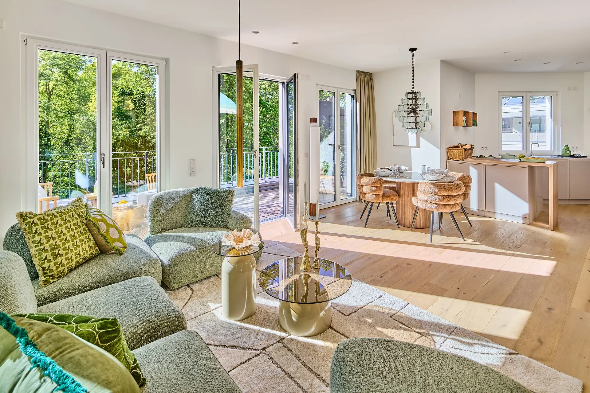 Helles Wohnzimmer mit Sofa, Glastisch, Essbereich und offener Küche, Zugang zum Balkon.