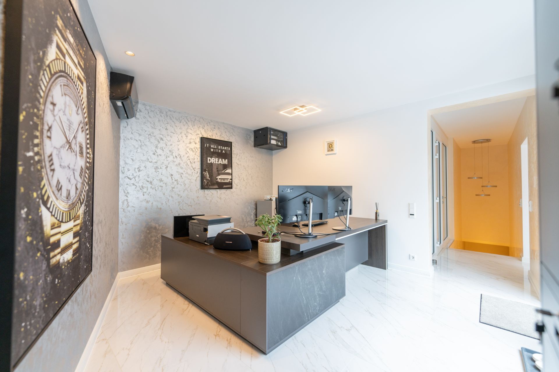 Modernes Arbeitszimmer mit großem Schreibtisch, Monitoren und Wandbild.