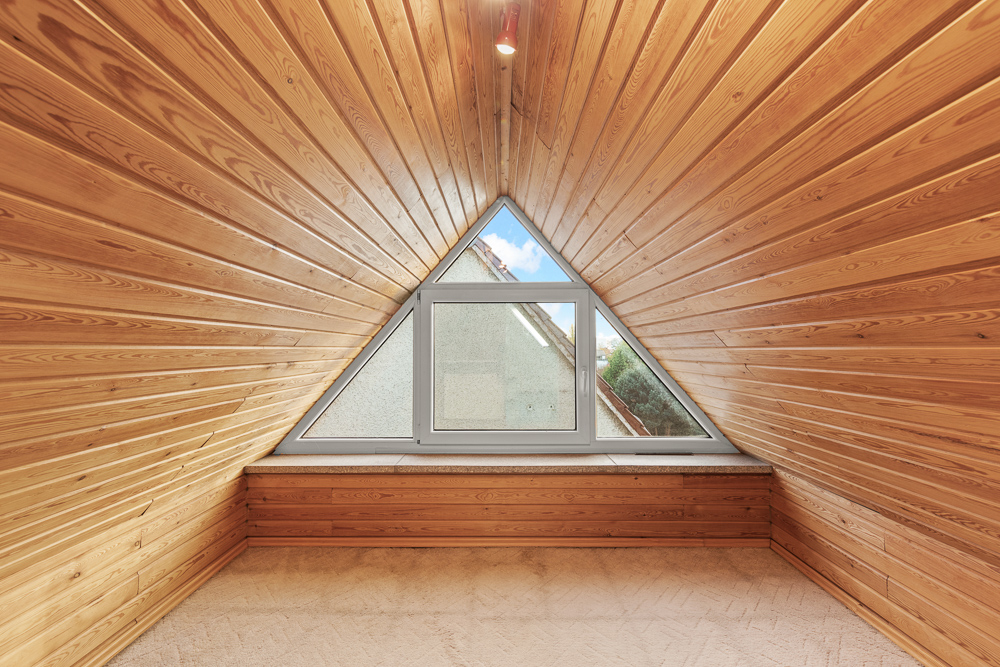 Dachgeschossraum mit Holzverkleidung und dreieckigem Fenster.