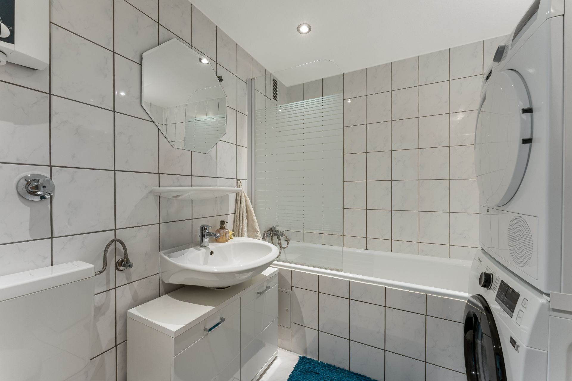 Modernes Badezimmer mit Badewanne, Waschbecken, Spiegel und Waschmaschine mit Trockner.