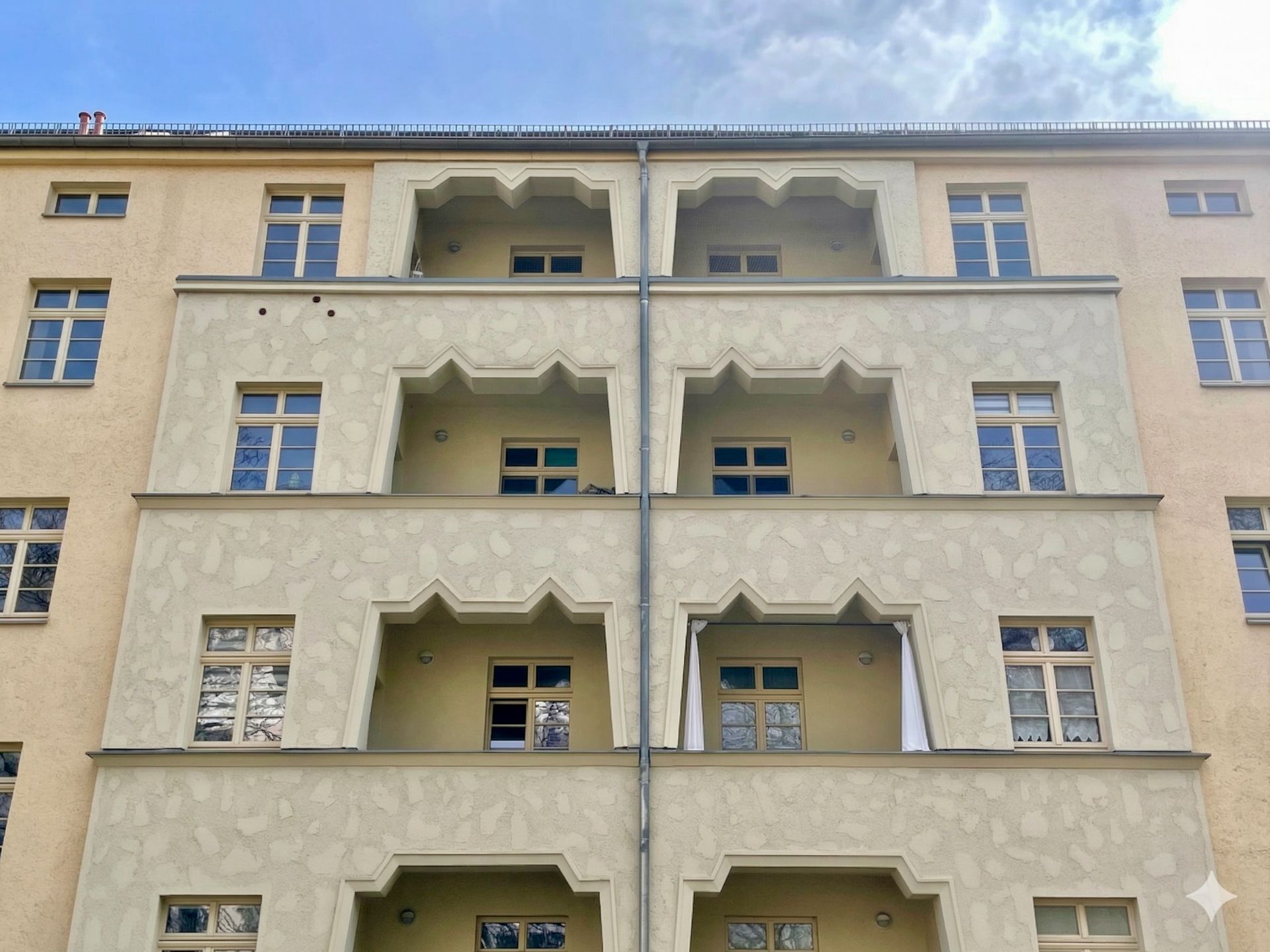 Mehrstöckiges Wohnhaus mit mehreren Balkonen und rechteckigen Fenstern.