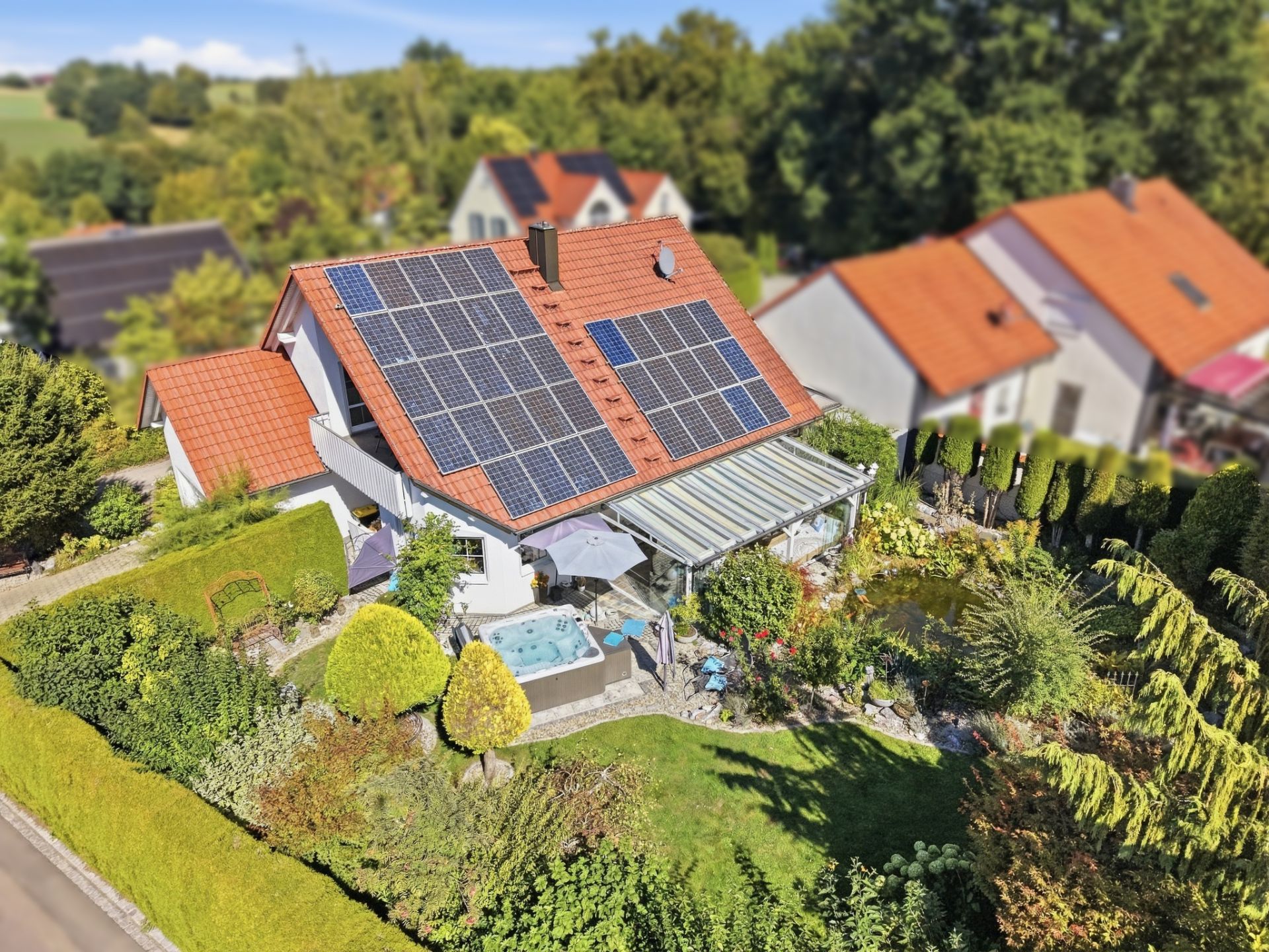 Einfamilienhaus mit Solarpanels auf dem Dach, Garten, Terrasse und Whirlpool.