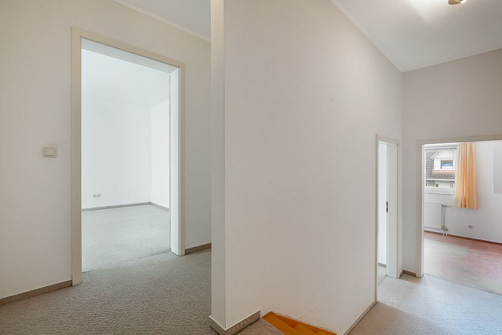 Heller Flur mit Teppichboden, Türen führen in verschiedene Zimmer einer Wohnung.
