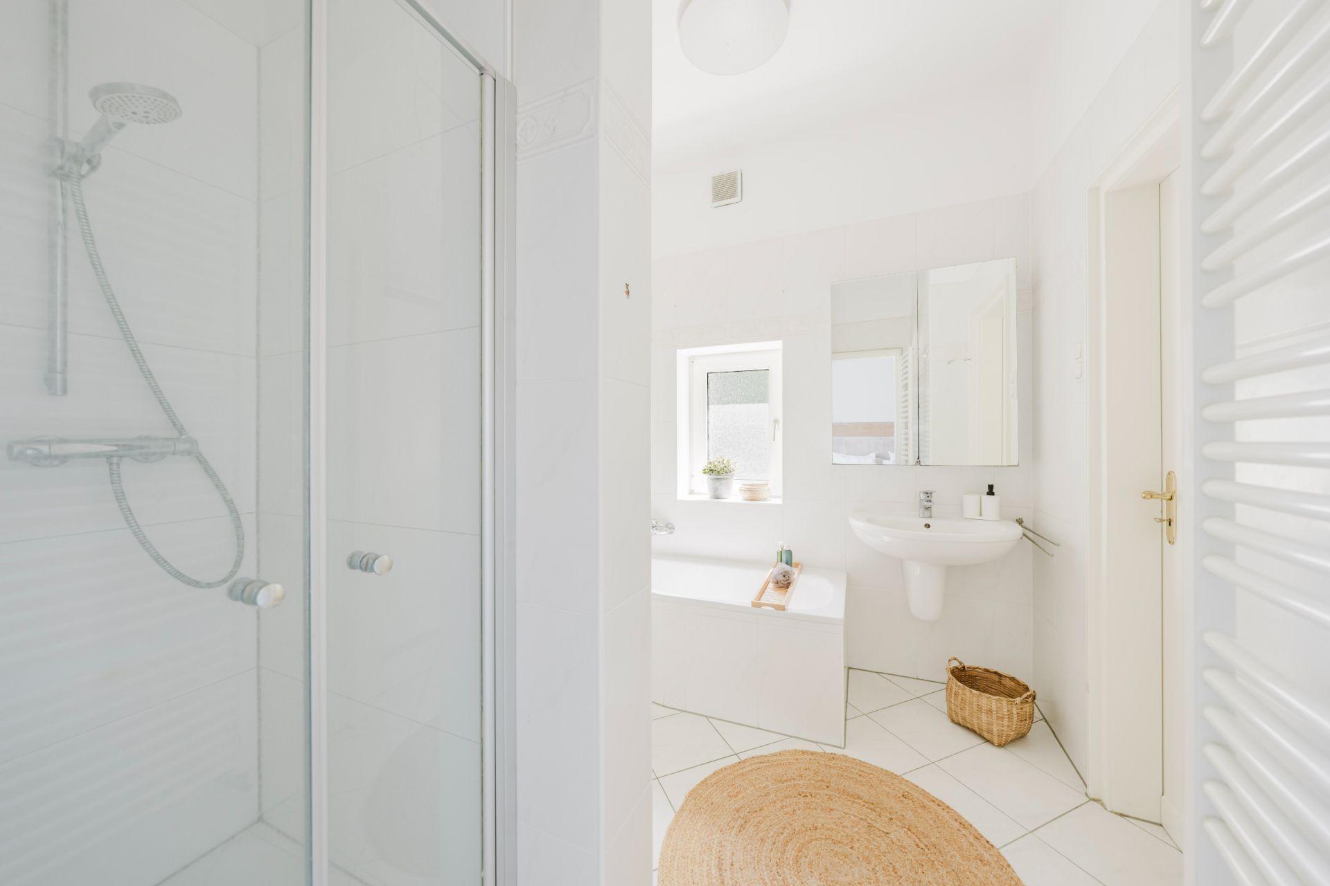 Modernes, helles Badezimmer mit Dusche, Badewanne, Waschbecken und Fenster.