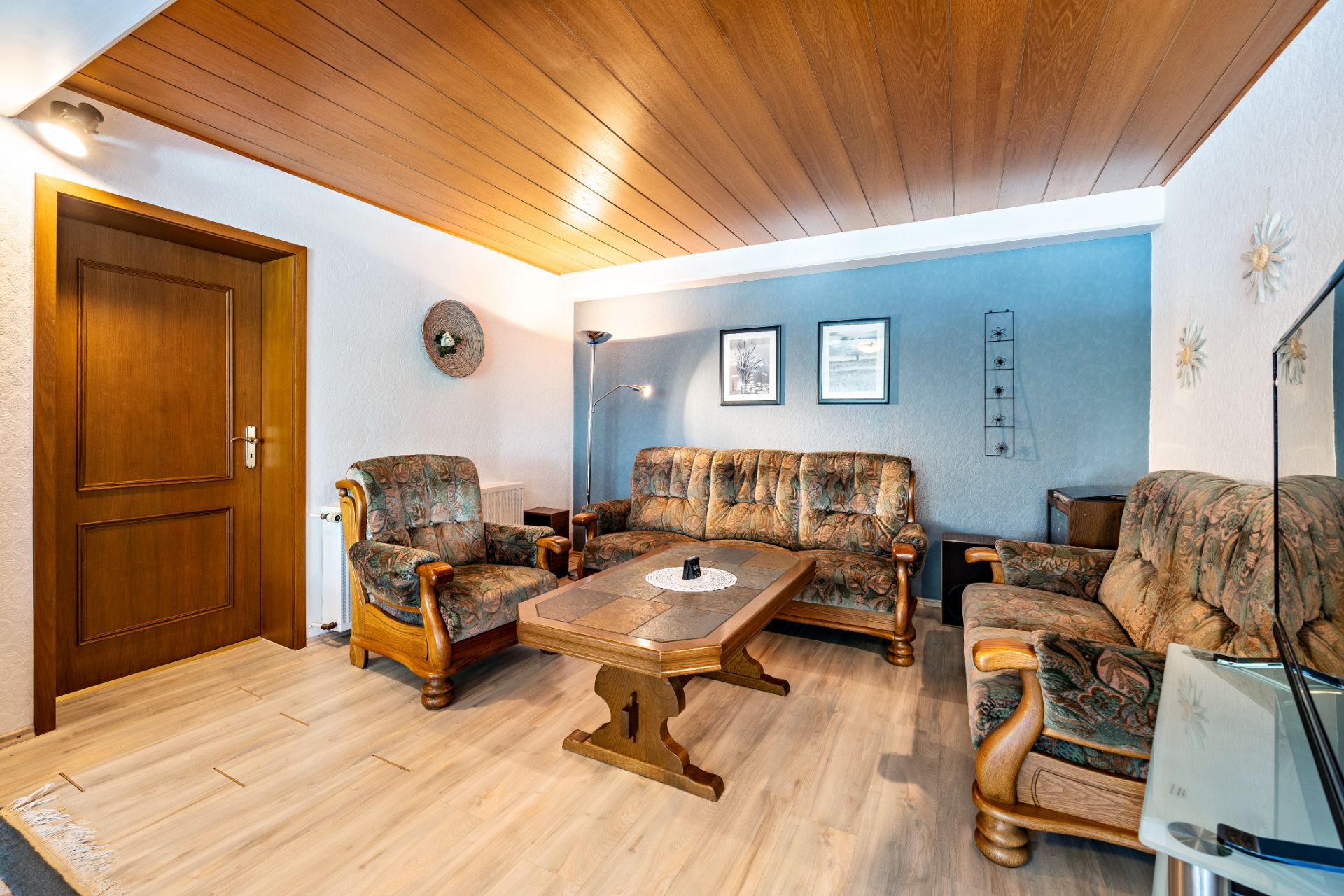 Wohnzimmer mit gemusterten Sofas, Holzdecke, Couchtisch und Wandbildern.