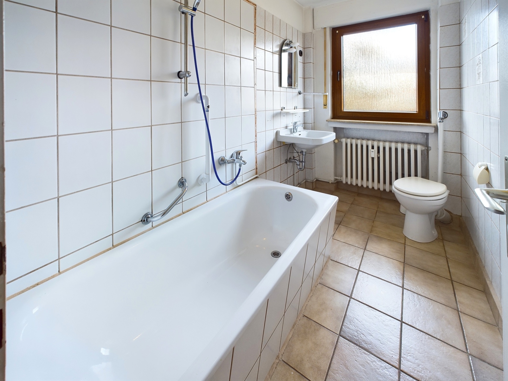 Helles Badezimmer mit Badewanne, WC, Waschbecken und Fenster.