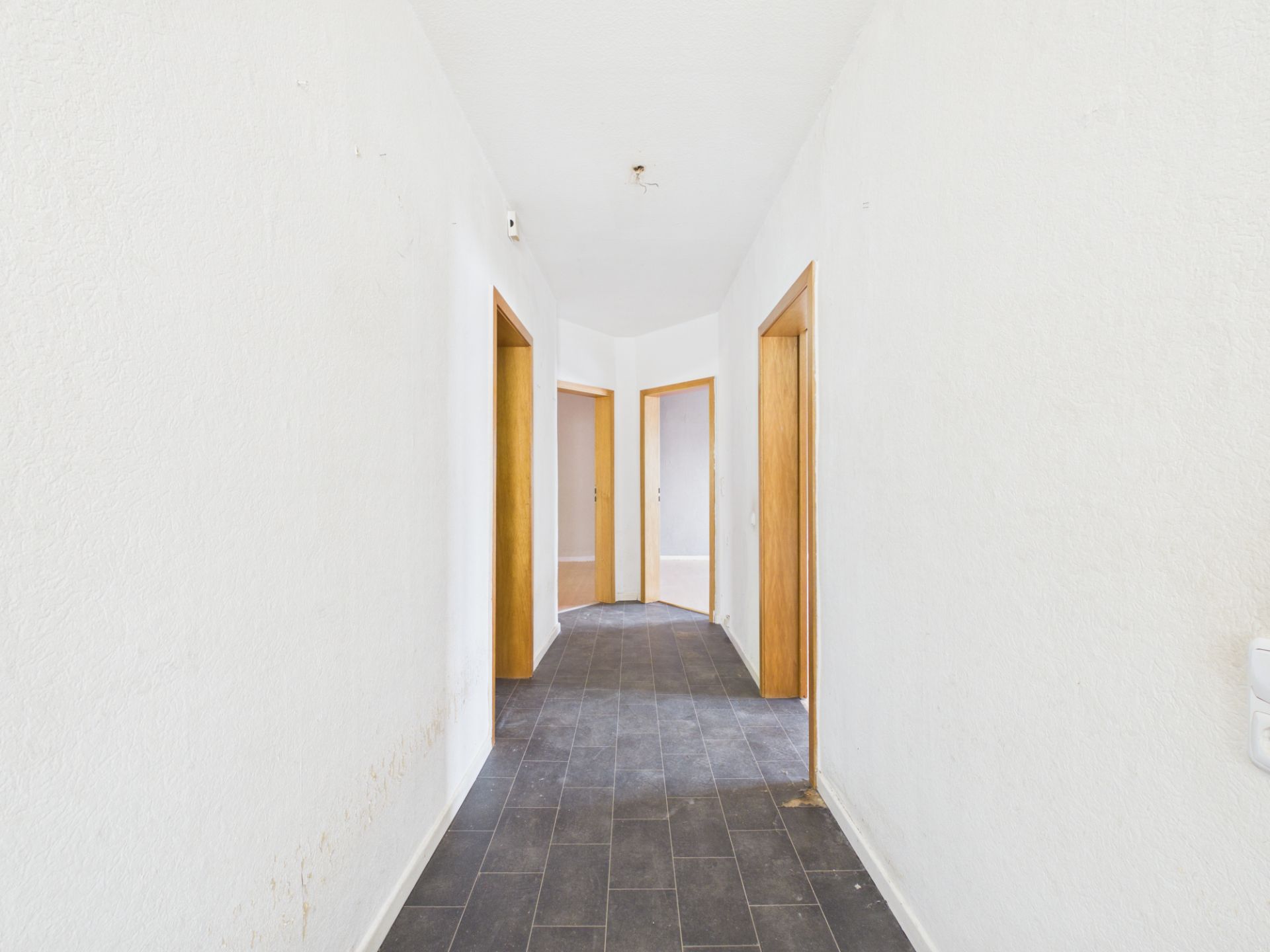 Heller Flur mit Fliesenboden und mehreren Türen in einer Wohnung.