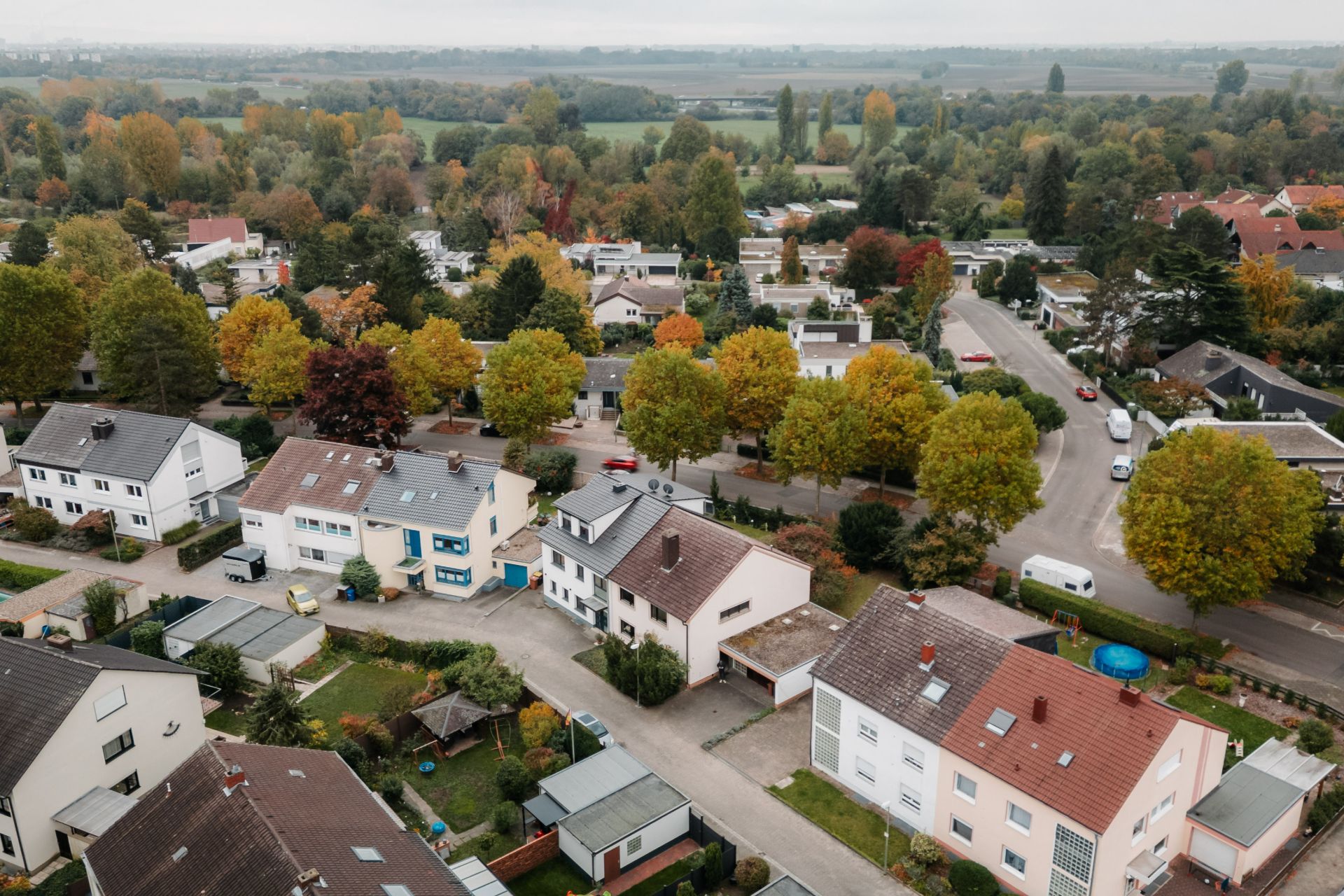 Luftaufnahme eines Wohngebiets mit mehreren Häusern und Bäumen entlang der Straßen.