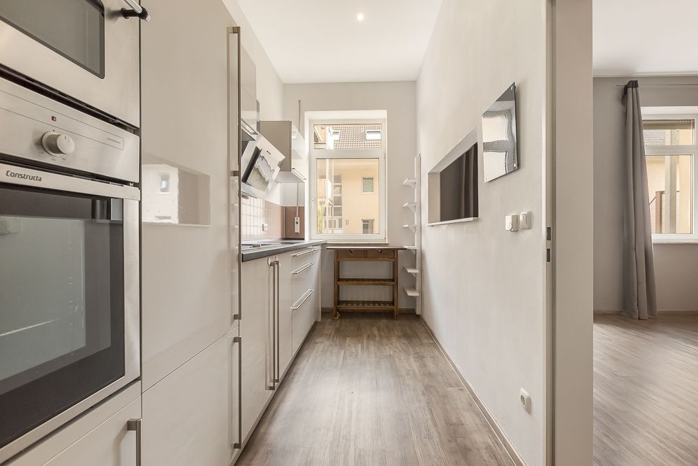 Moderne Küche mit Einbaugeräten, Holzfußboden und großem Fenster in einer Wohnung.