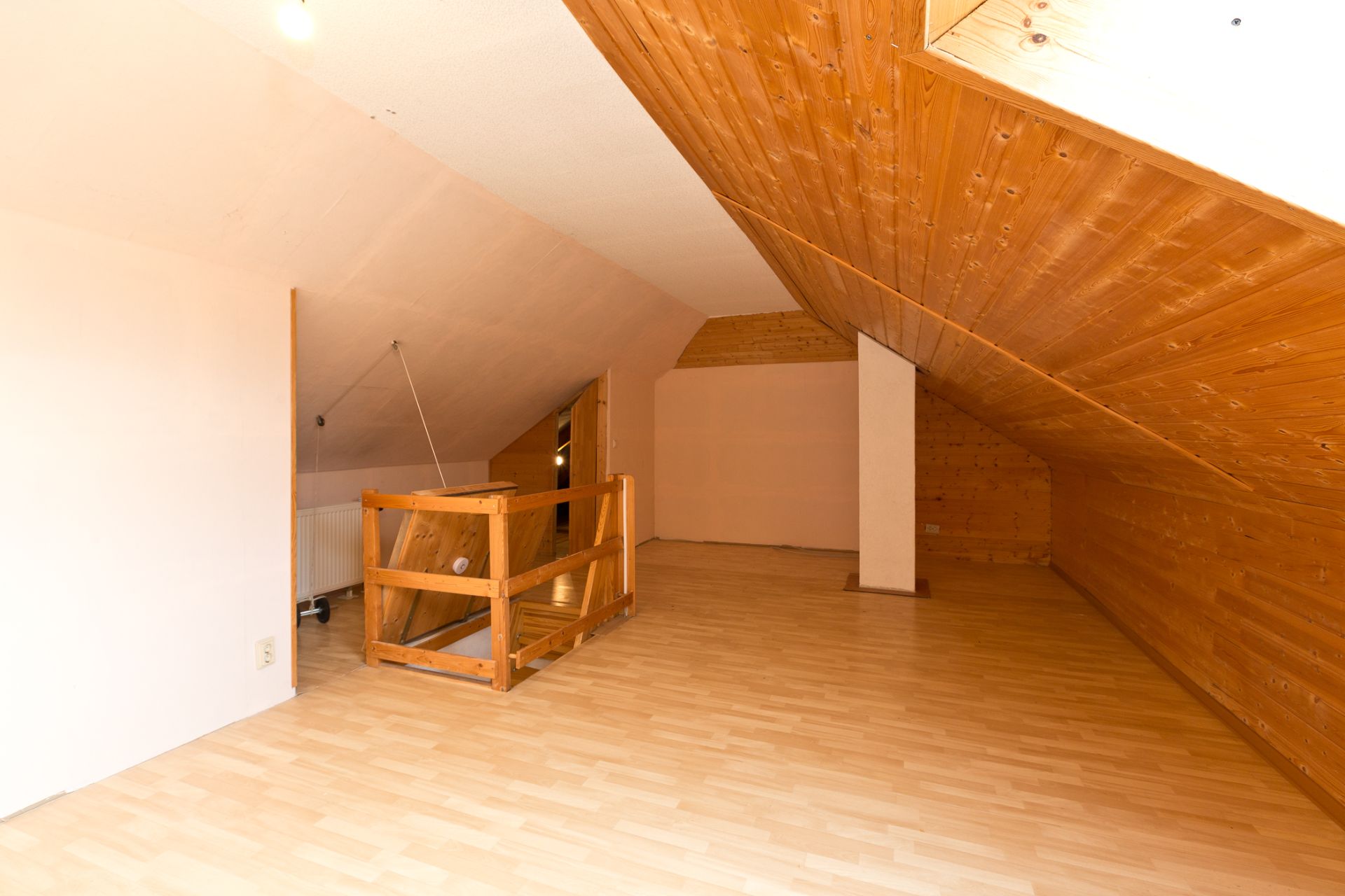 Heller Dachbodenraum mit Holzverkleidung und Parkettboden, sichtbare Treppe in der Ecke.