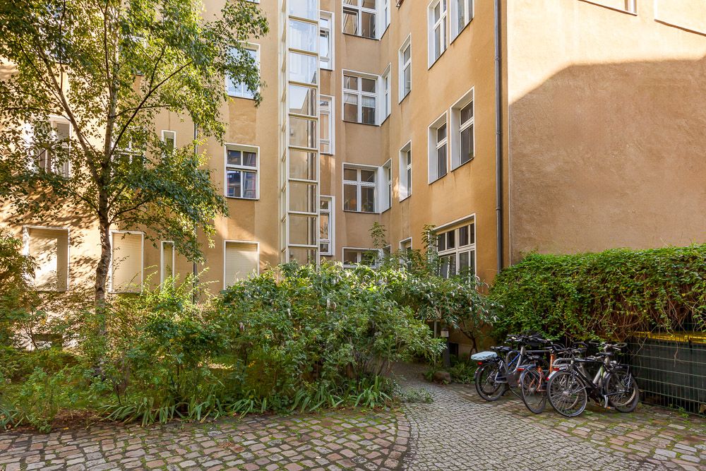 Hof eines Wohnhauses mit Pflanzen, Kopfsteinpflaster und mehreren geparkten Fahrrädern.
