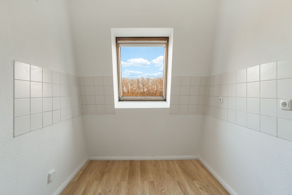 Kleiner leerer Raum mit Fliesen an den Wänden, Holzfußboden und Fenster mit Ausblick.