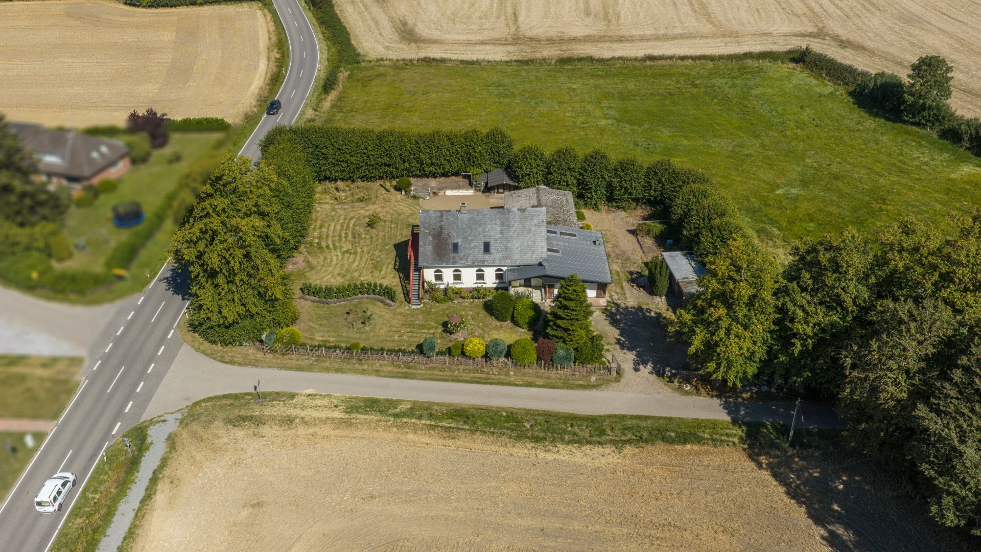 Luftaufnahme eines Einfamilienhauses mit großem Garten und umgebenden Feldern.