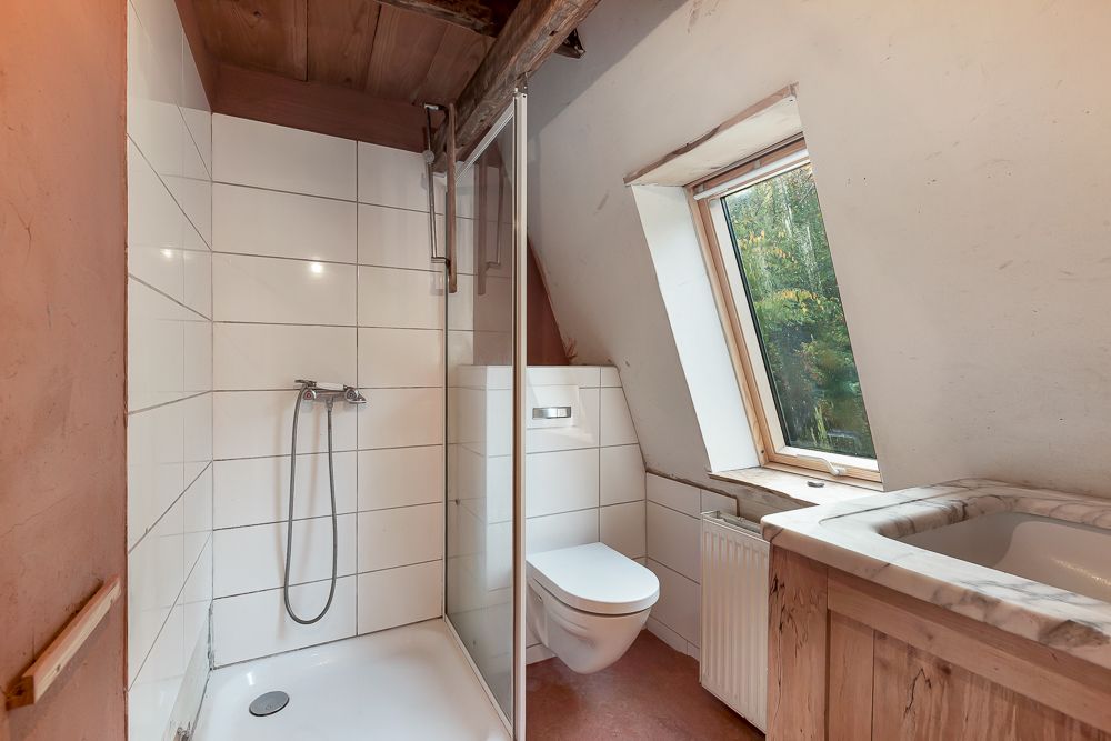 Kleines Badezimmer mit Dusche, WC, Waschbecken und Fenster zur Gartenseite.