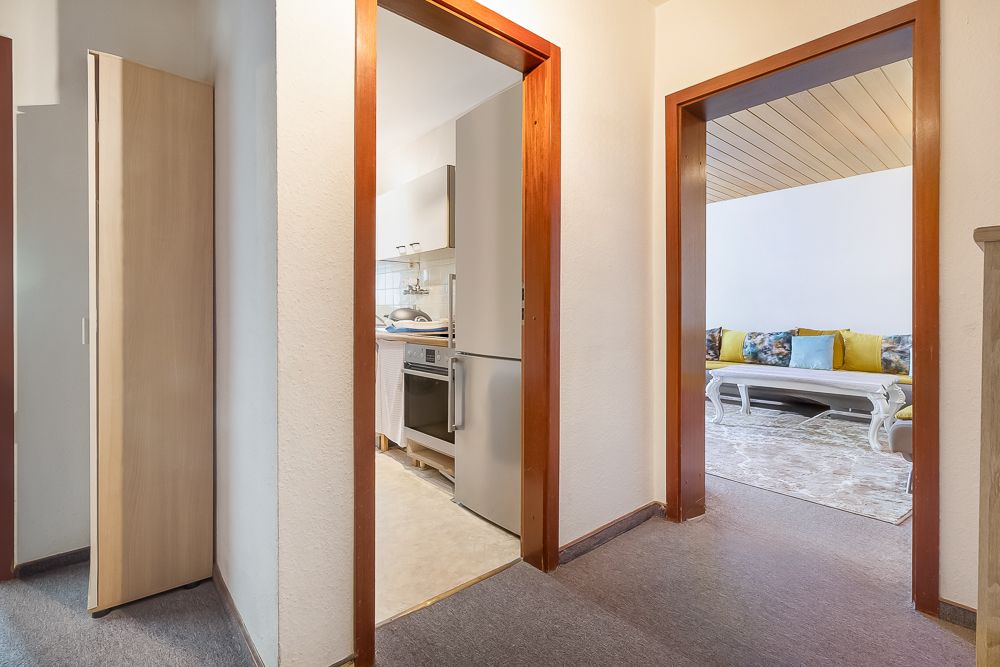 Flur mit Blick in eine Küche und ein Wohnzimmer mit Sofa und Couchtisch.