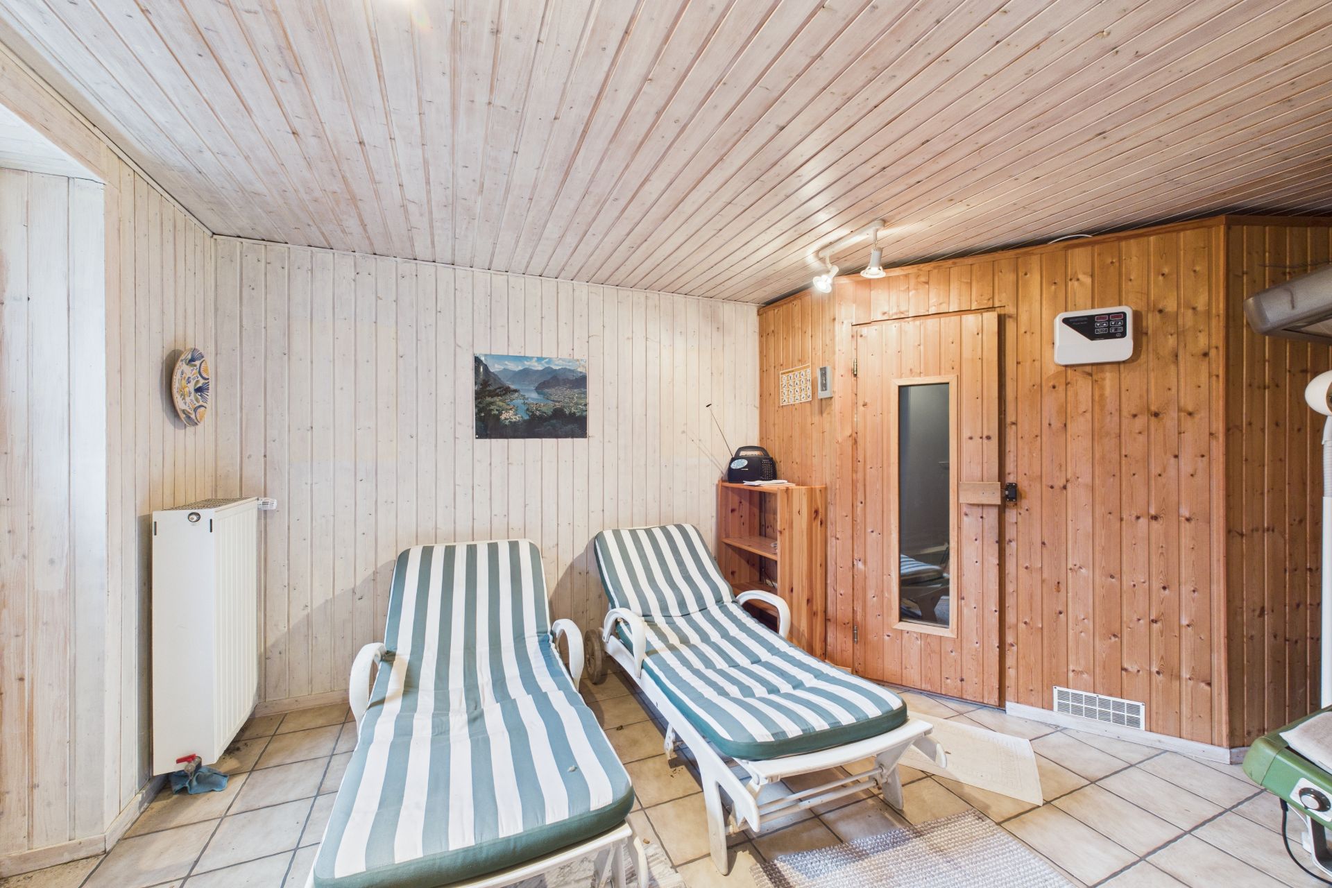 Zwei Liegestühle stehen in einem Raum mit Holzdecke und Sauna.