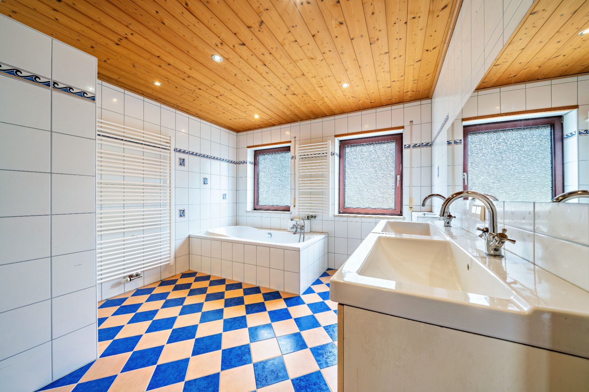 Modernes Badezimmer mit Eckbadewanne, zwei Waschbecken und buntem Fliesenboden.