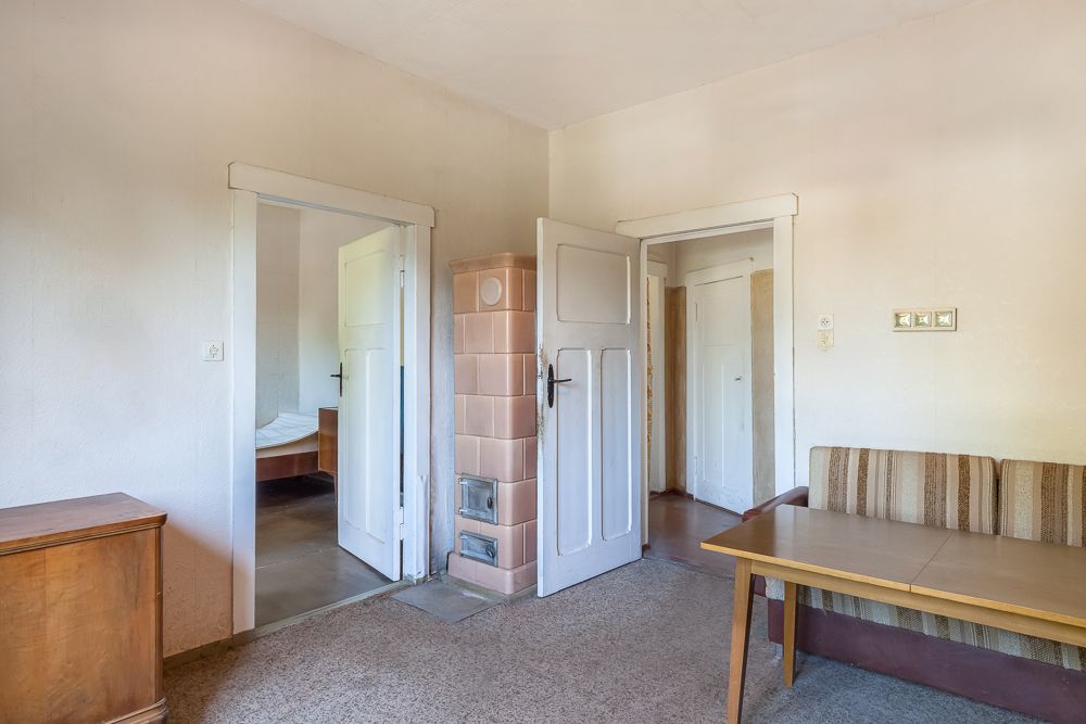 Wohnzimmer mit Tisch, Sofa, Kommode und offenstehenden Türen zu anderen Räumen.