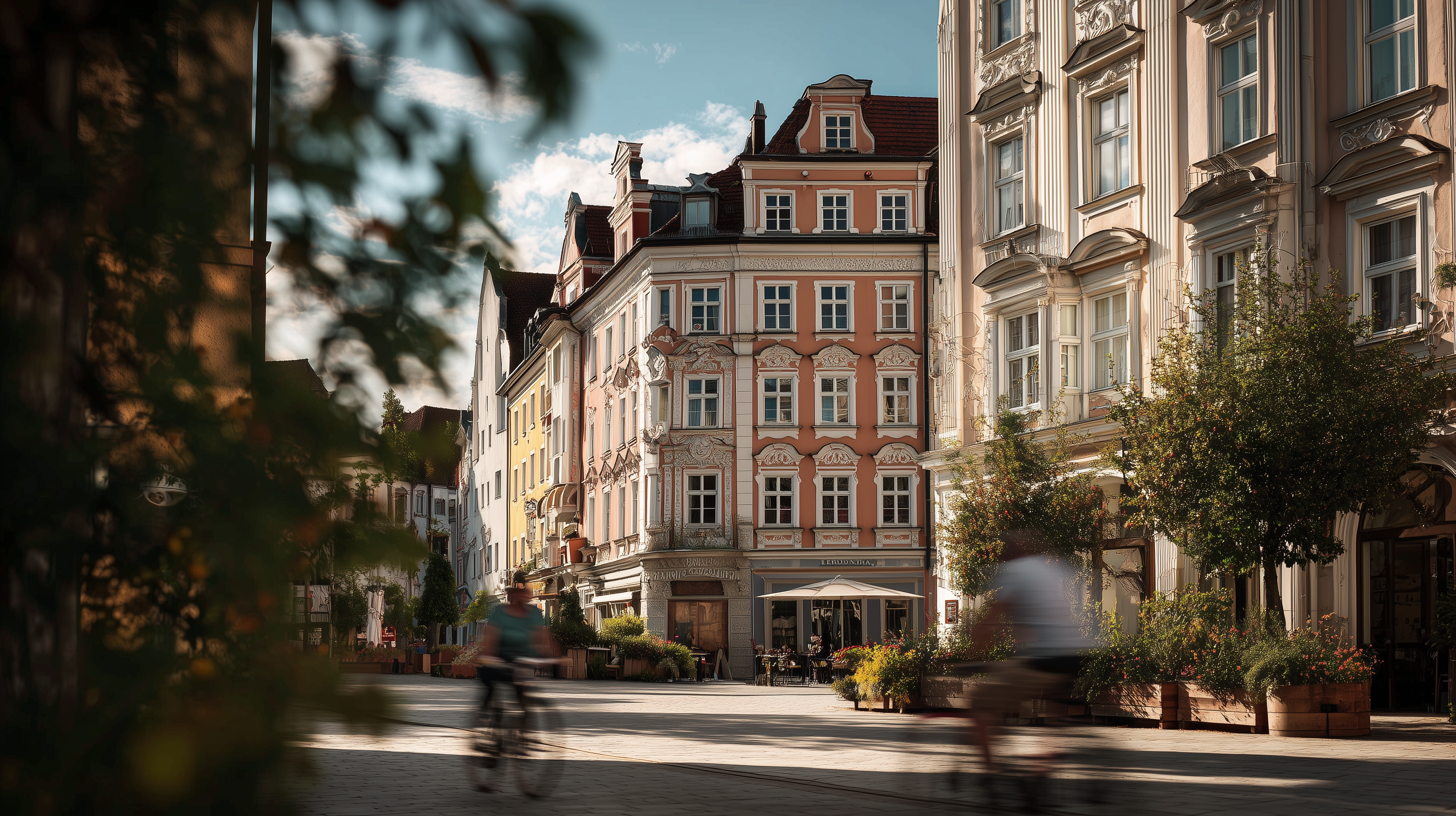 Mehrstöckiges Wohnhaus mit klassischer Fassade an einer belebten Straße, Radfahrer im Vordergrund.