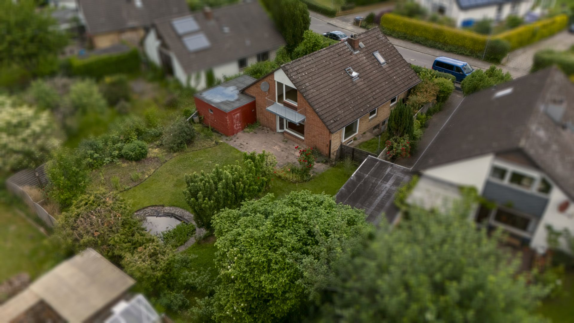 Luftaufnahme eines Einfamilienhauses mit Garten und Nebengebäude in einer Wohngegend.
