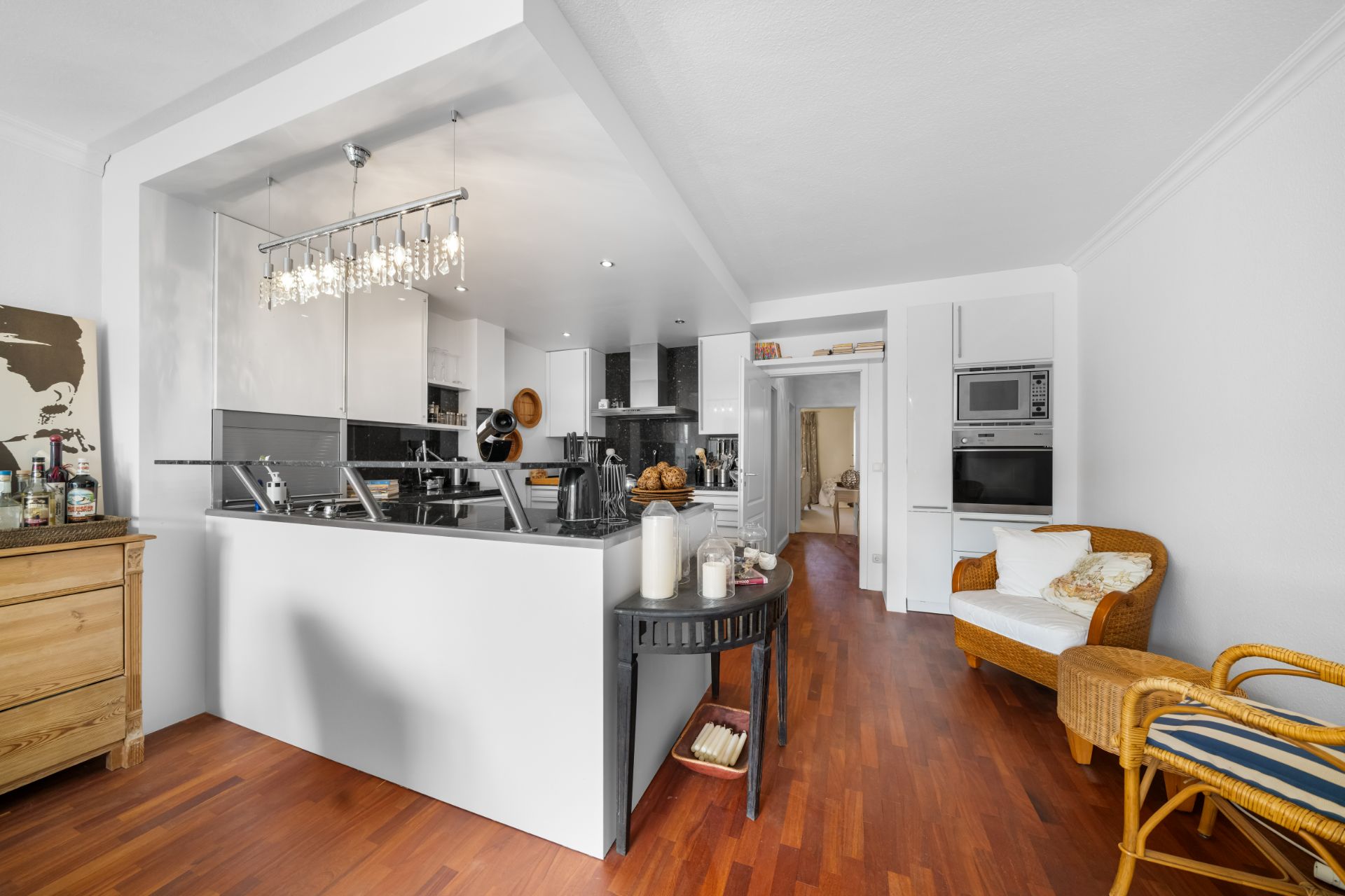 Moderne offene Küche mit Hängelampen, Holzboden und Sitzbereich in einem Wohnraum.