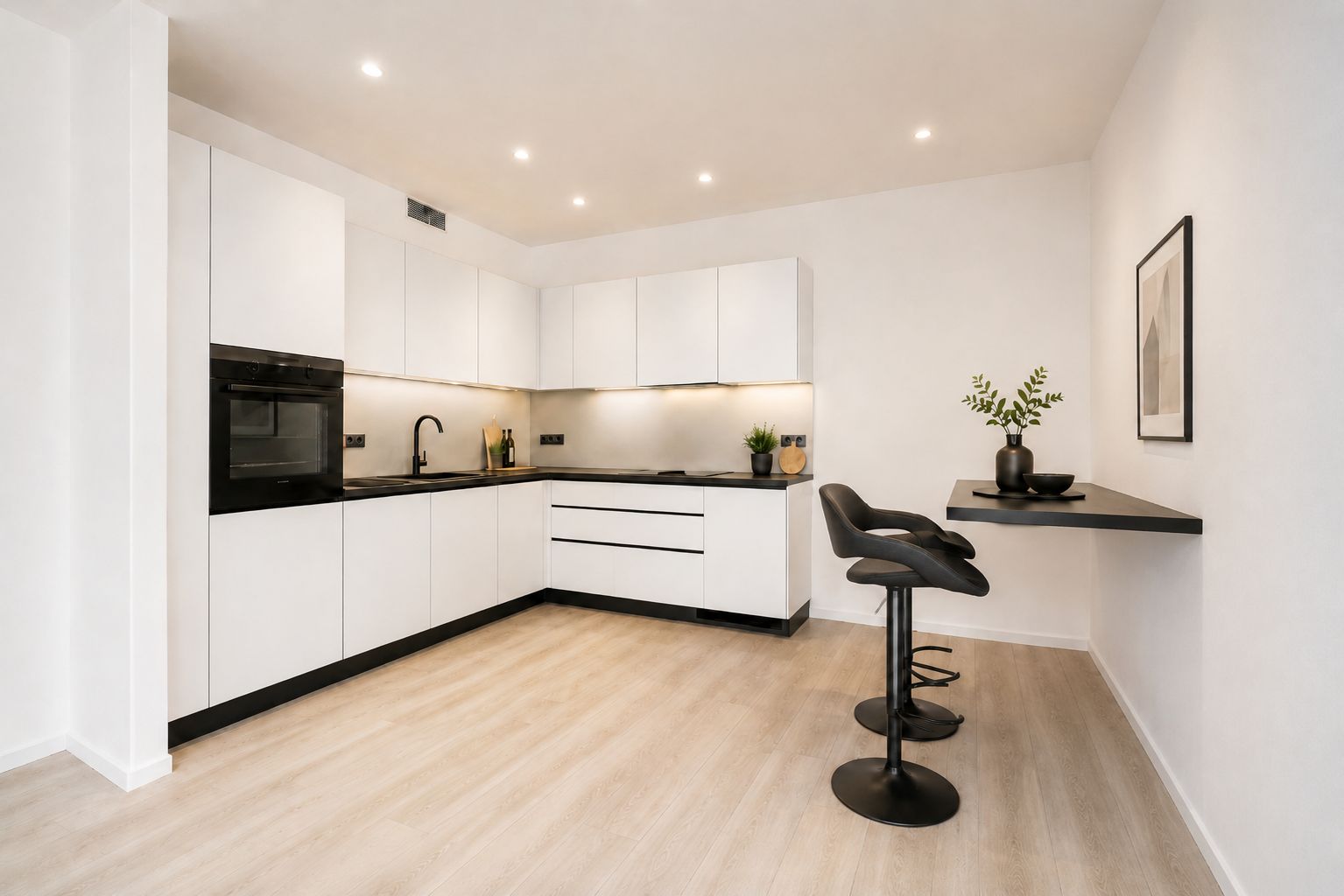 Moderne weiße Einbauküche mit schwarzer Arbeitsplatte und zwei Barhockern an einem Wandtisch.