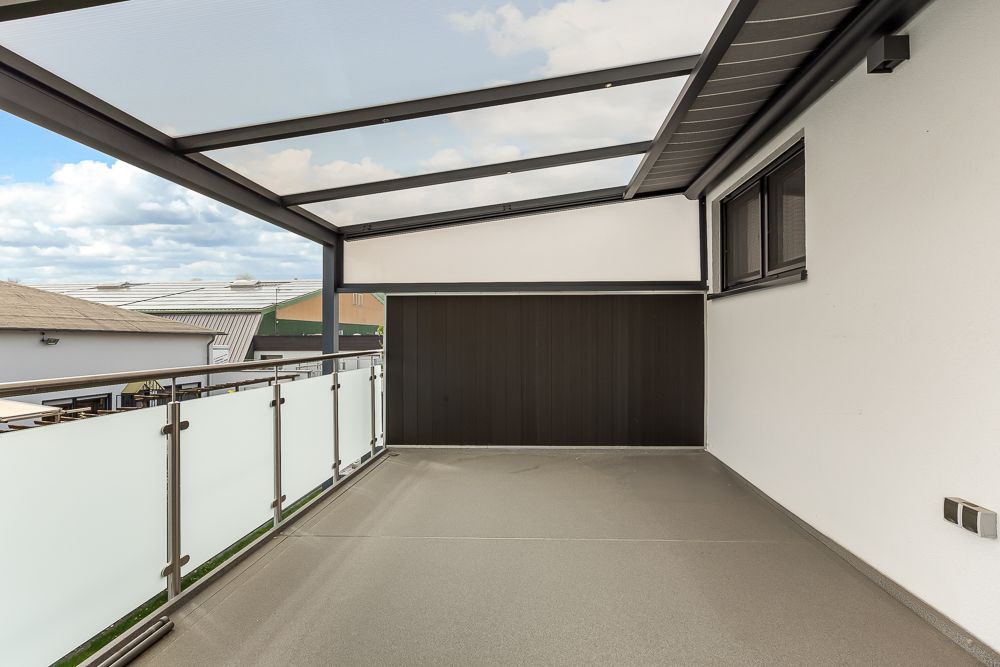 Überdachter Balkon mit Glasgeländer und seitlichem Fenster, moderner Stil.