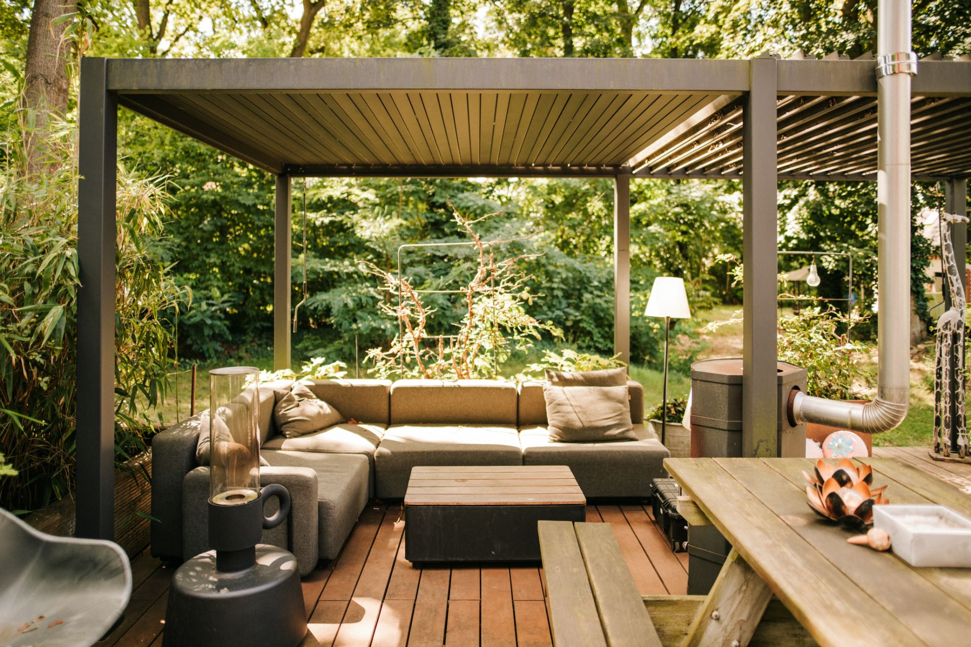 Überdachte Terrasse mit Ecksofa, Couchtisch und Holzboden im Garten.