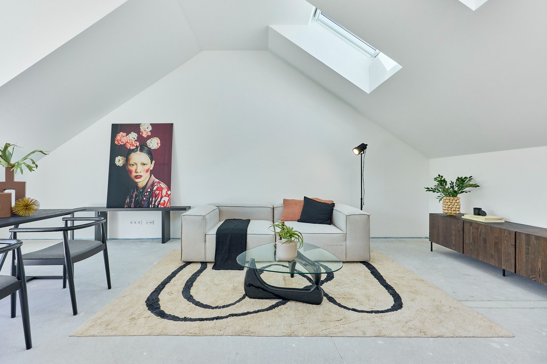 Modernes Wohnzimmer mit Sofa, Glastisch, Teppich, Pflanzen und großem Porträt an der Wand.
