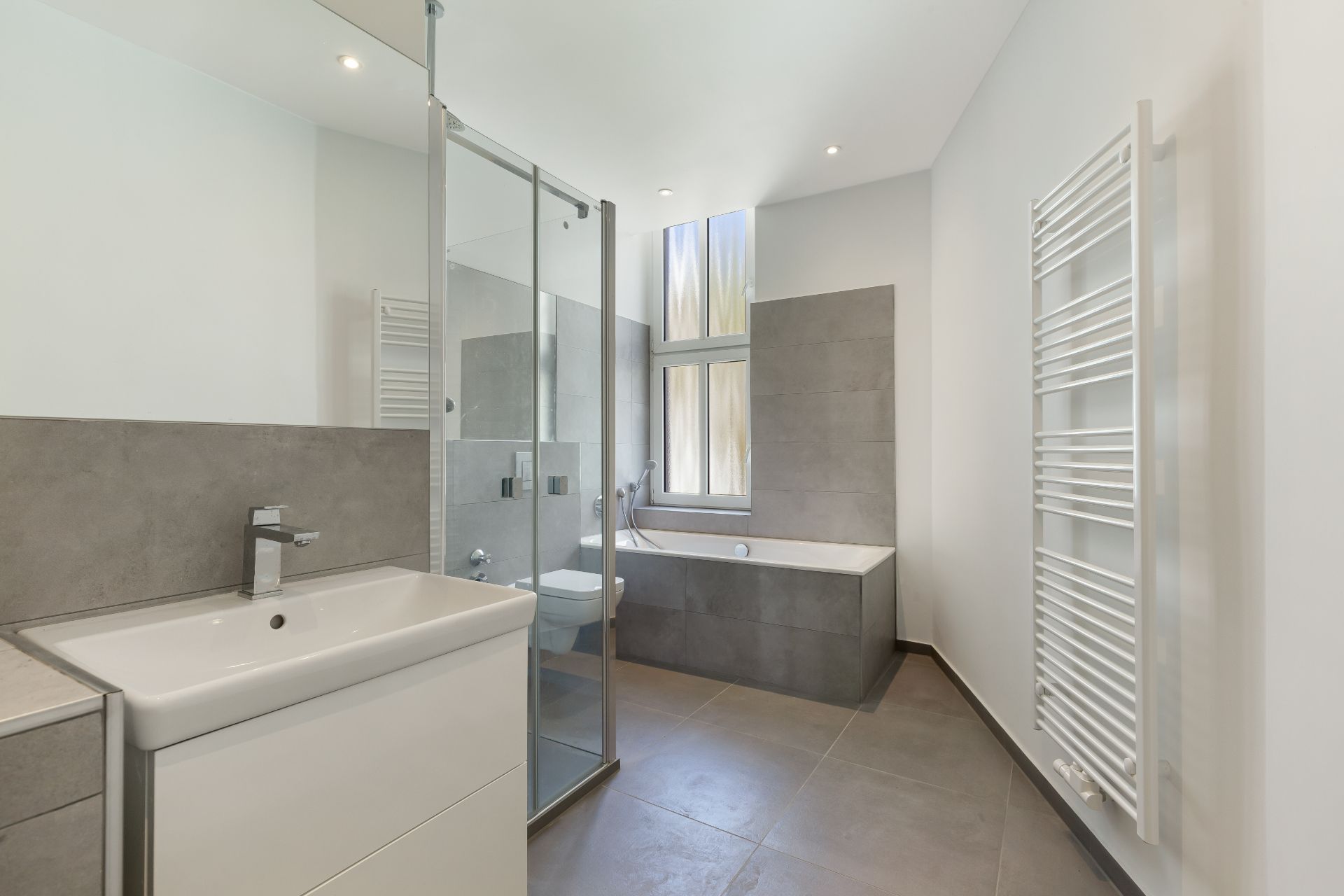 Modernes Badezimmer mit Dusche, Badewanne, Waschbecken und Handtuchheizkörper.