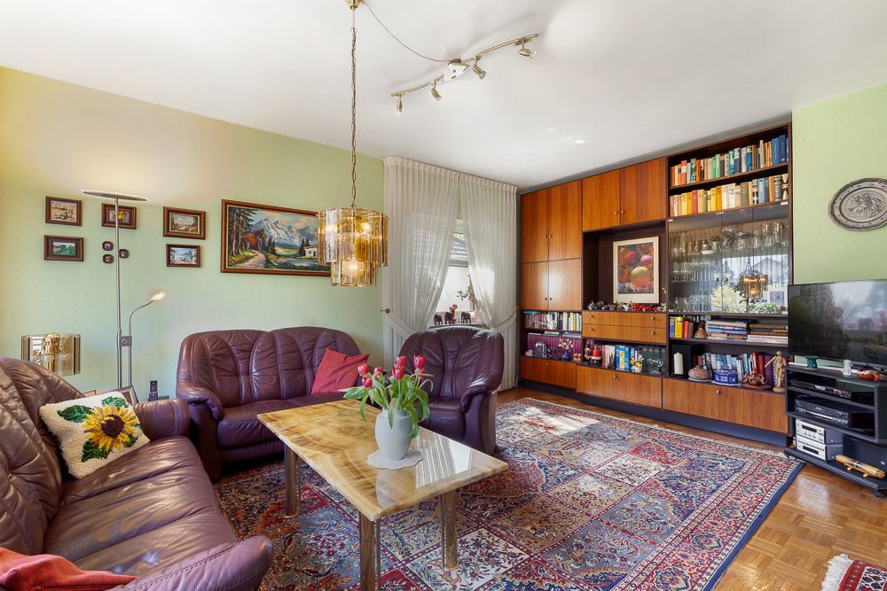 Wohnzimmer mit Ledersofas, Teppich, Couchtisch, Regalwand und Dekorationen.