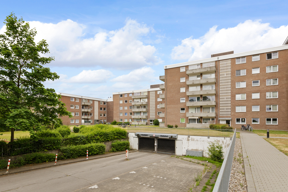 Mehrstöckige Wohngebäude aus Backstein mit Balkonen und einer Zufahrt zur Tiefgarage.