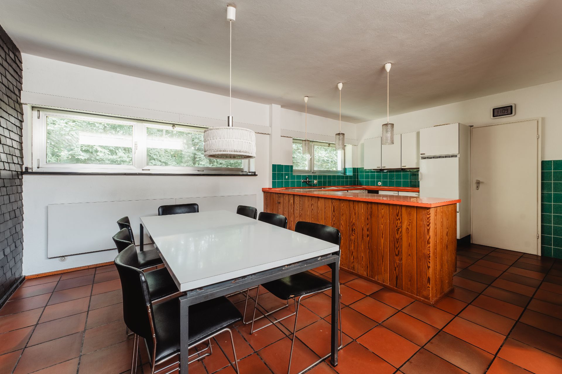 Moderne Küche mit Esstisch, schwarzen Stühlen und Holz-Theke mit grünen Fliesen.