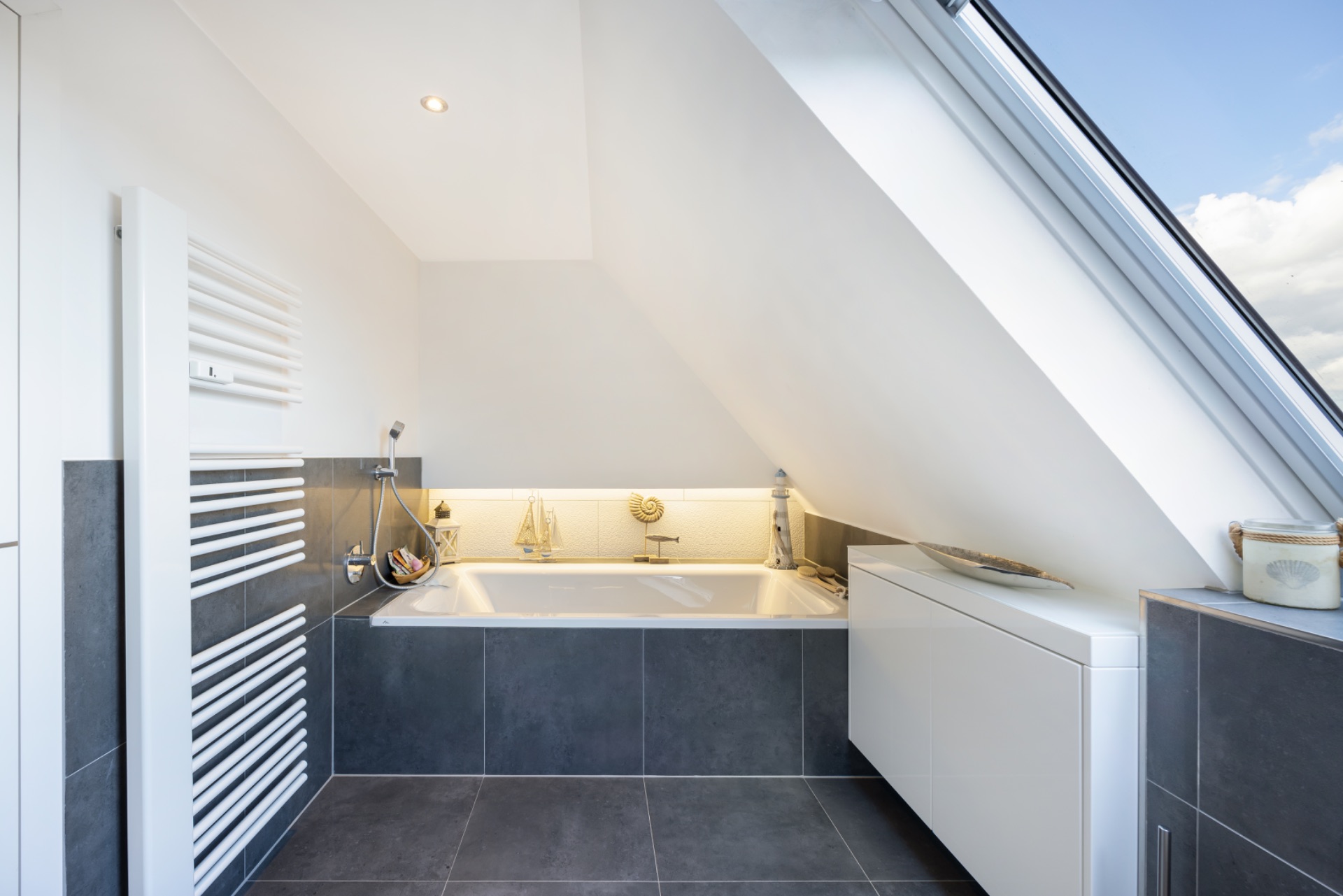 Modernes Badezimmer mit Badewanne unter Dachschräge und großem Dachfenster.