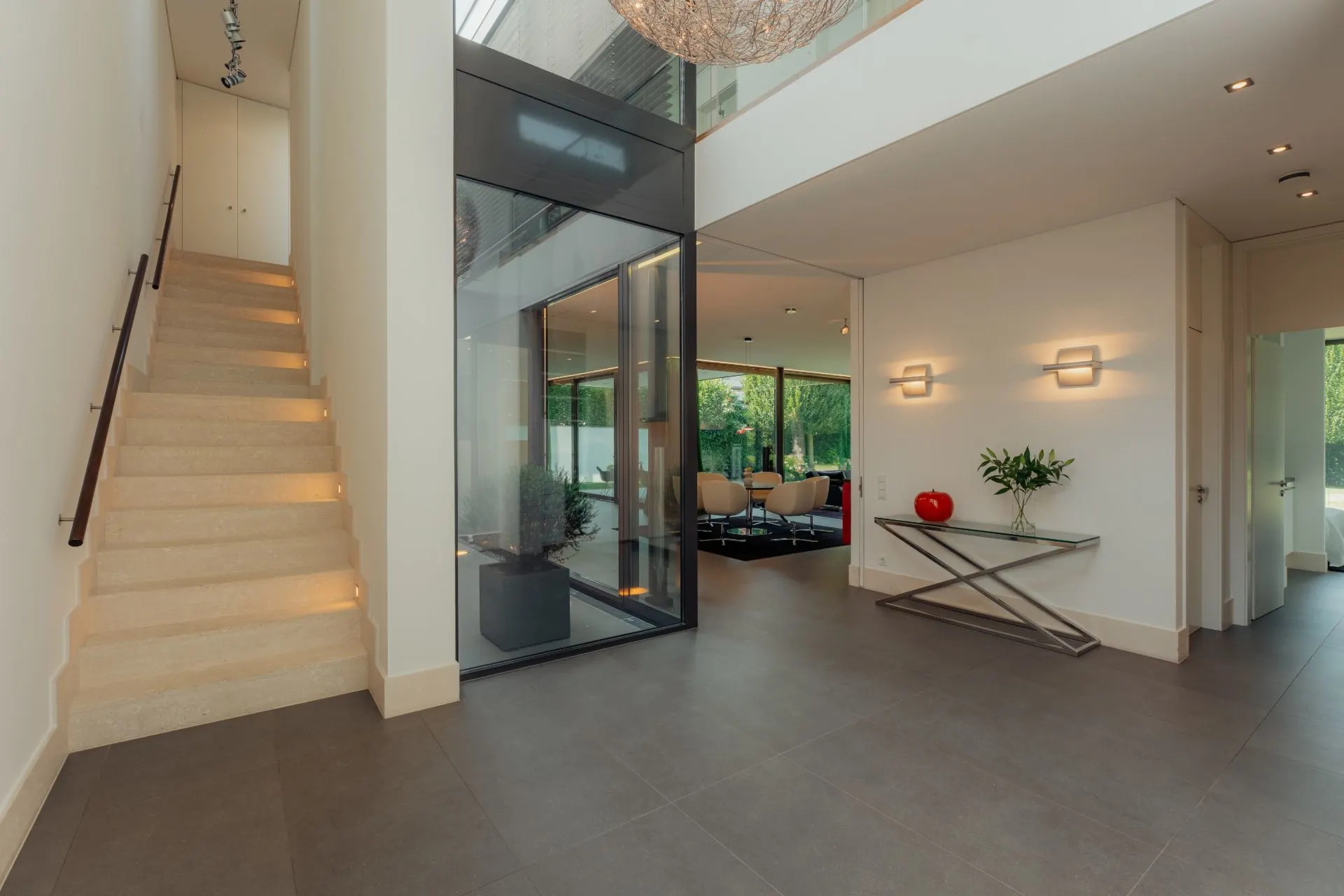Moderner Eingangsbereich mit Treppe, Glaselementen und Konsole mit Dekoration.