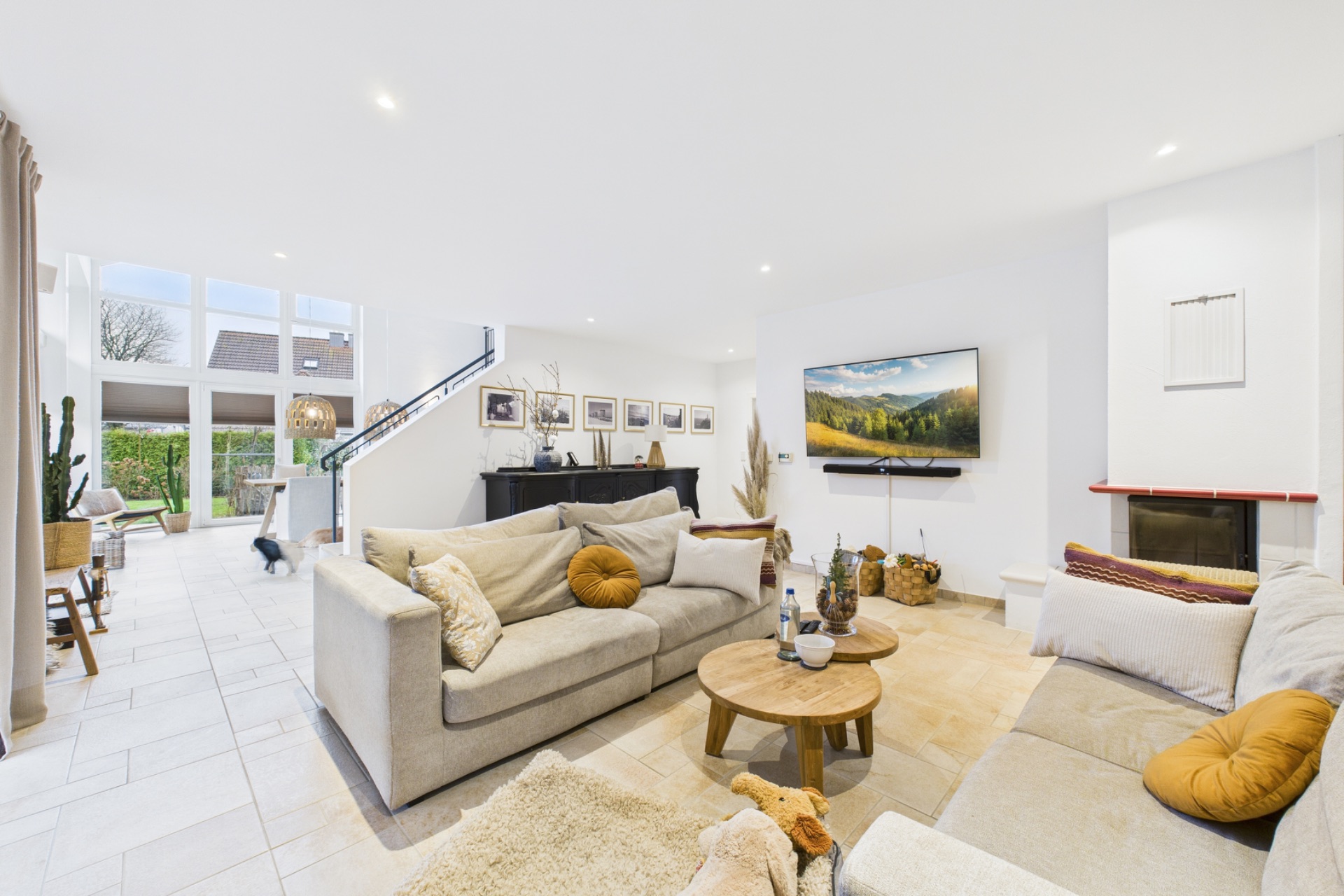 Helles Wohnzimmer mit zwei Sofas, Couchtisch, Kamin und großem Fensterfront.