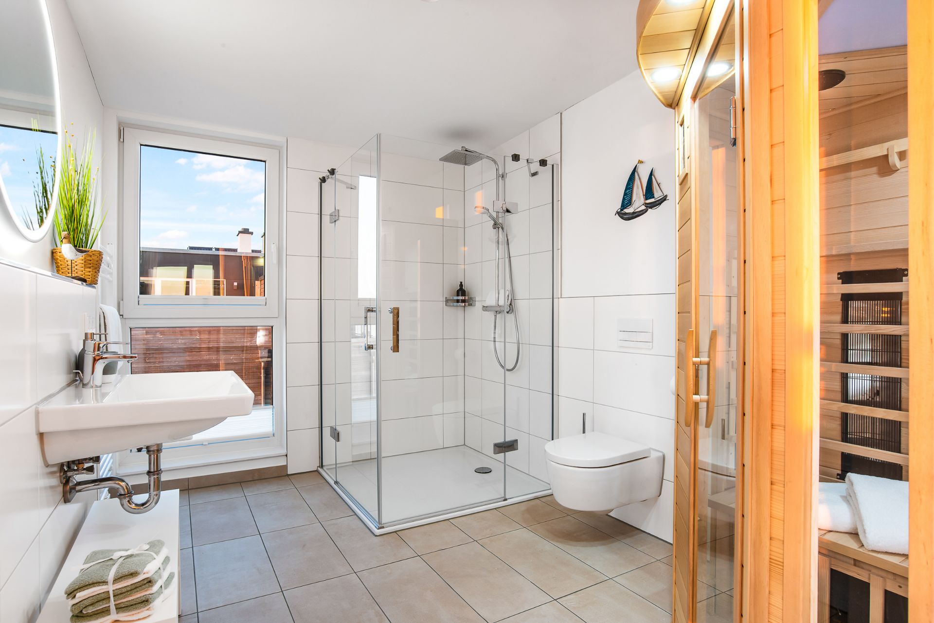 Helles Badezimmer mit Dusche, WC, Waschbecken und einer Sauna aus Holz.