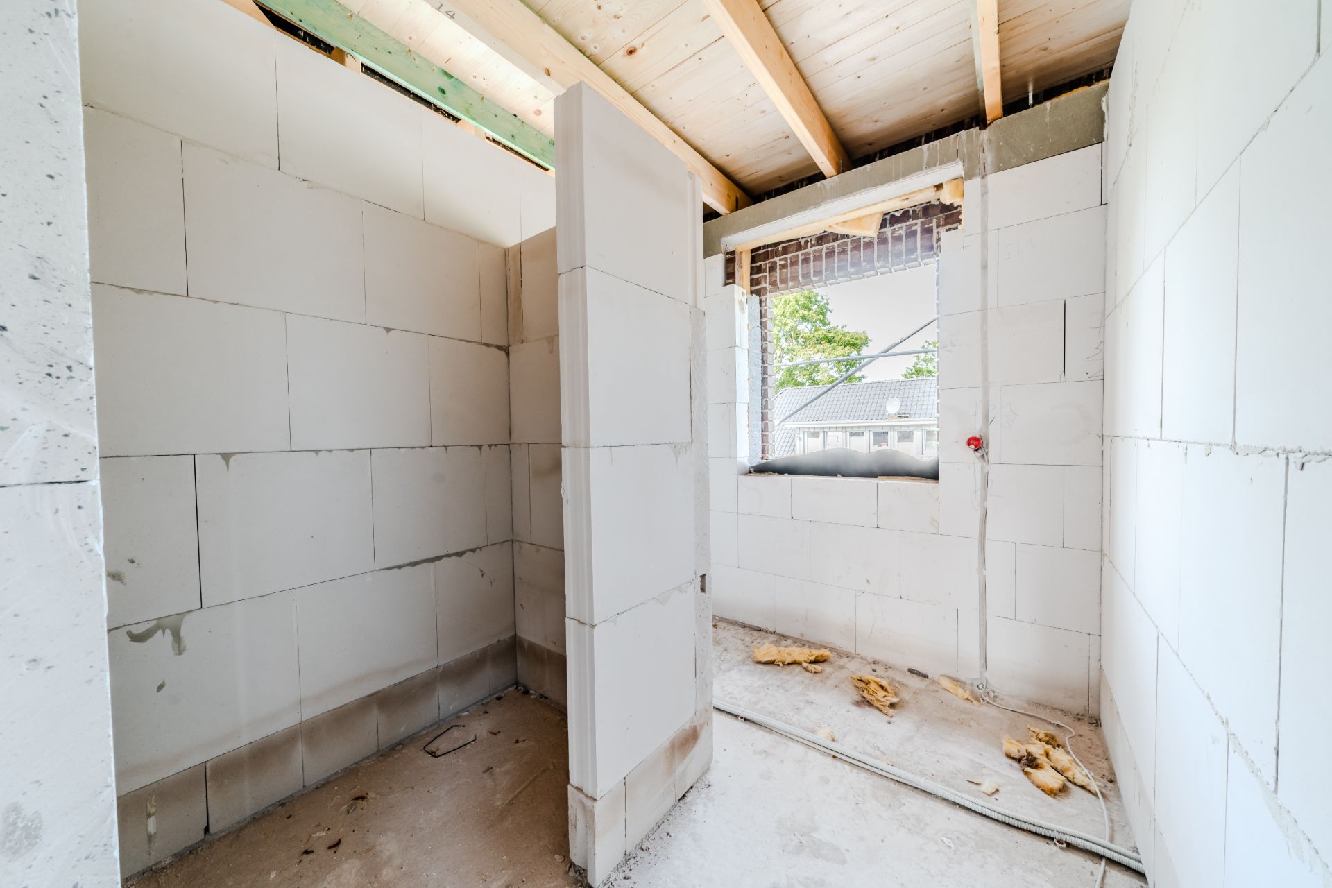 Rohbau eines Zimmers mit offenem Fenster und unverputzten Wänden.