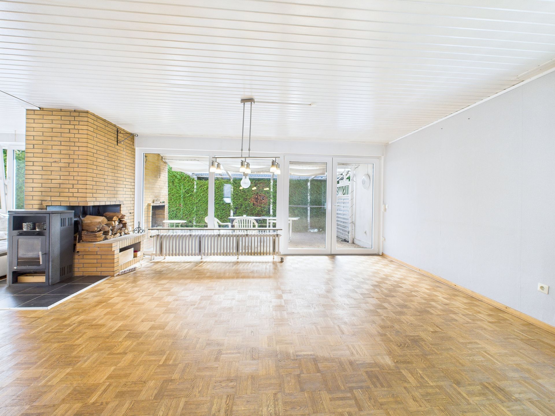 Helles Wohnzimmer mit Parkettboden, Kamin und großen Fenstern zur Terrasse.