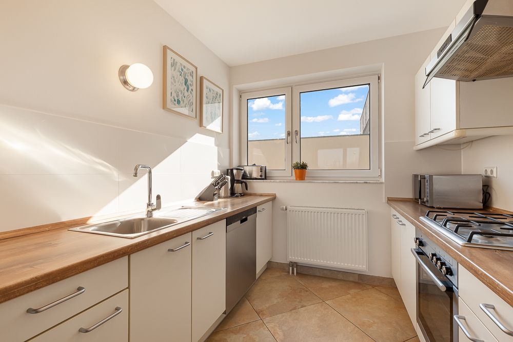 Moderne Küche mit Holzarbeitsplatten, Spüle, Gasherd, Fenster und Küchengeräten.