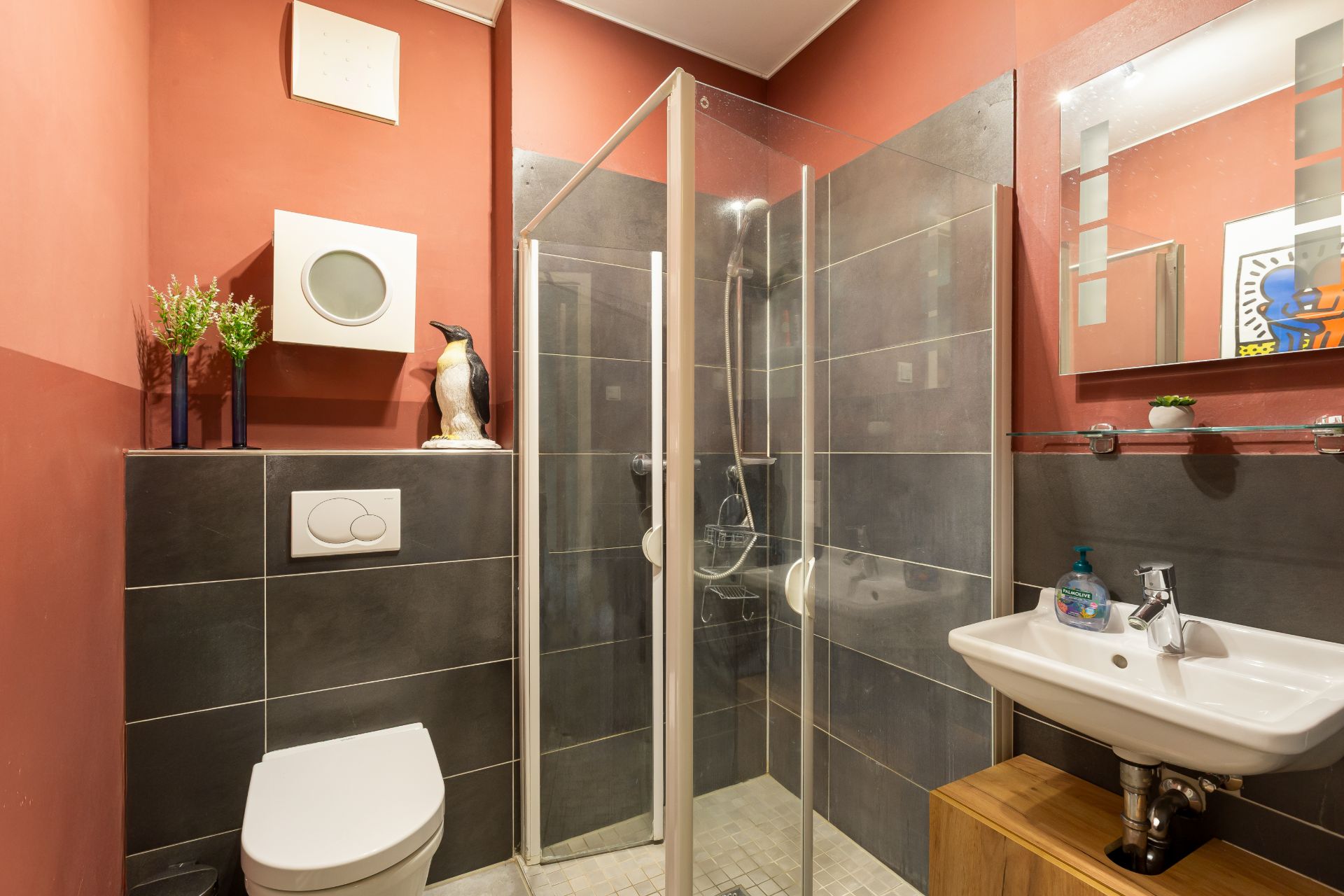Modernes Bad mit Dusche, WC, Waschbecken, Spiegel und dekorativen Elementen.