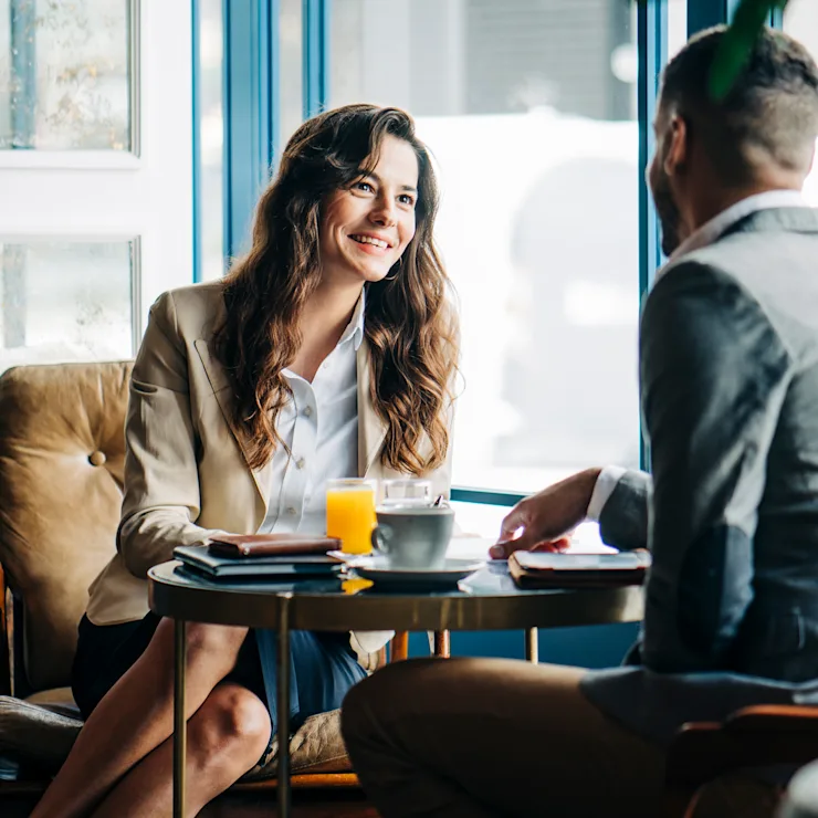 Zwei Personen sitzen am Tisch und unterhalten sich freundlich bei Getränken.
