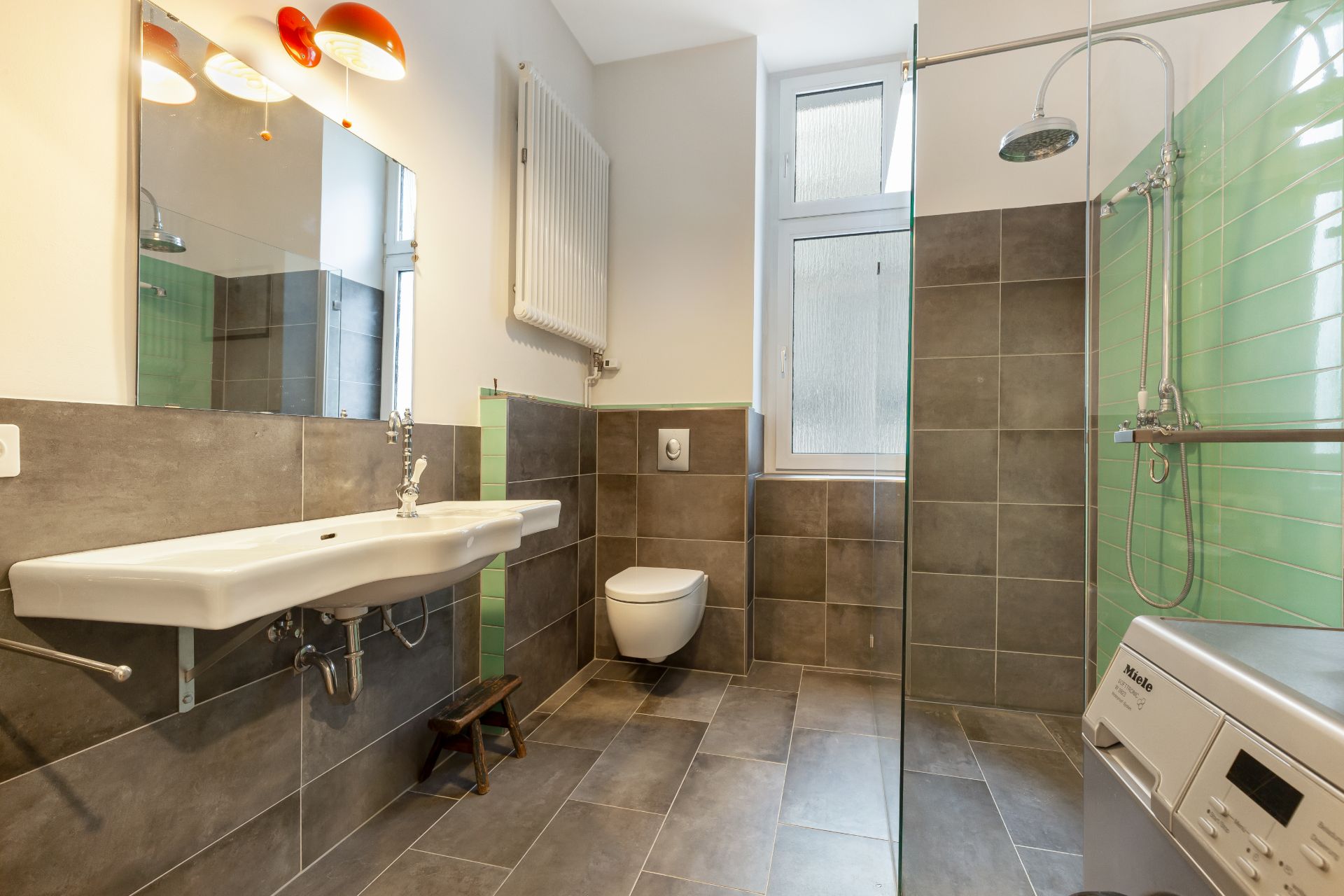 Modernes Badezimmer mit Waschbecken, Toilette, Dusche, Fenster und Waschmaschine.