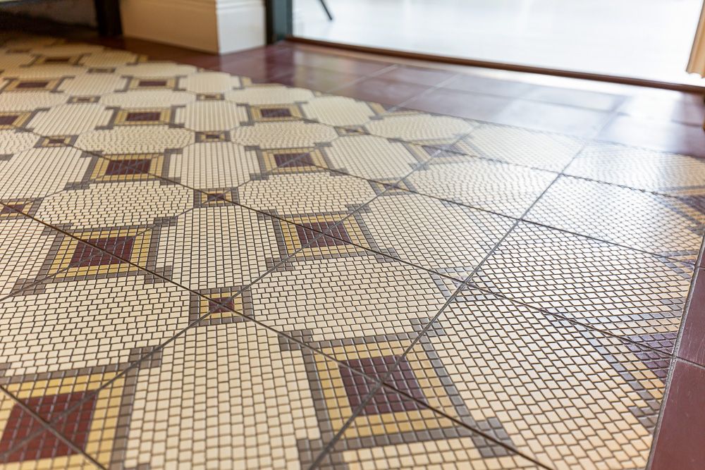Nahaufnahme von einem Boden mit geometrischen, gemusterten Fliesen in Beige, Gelb und Rot.