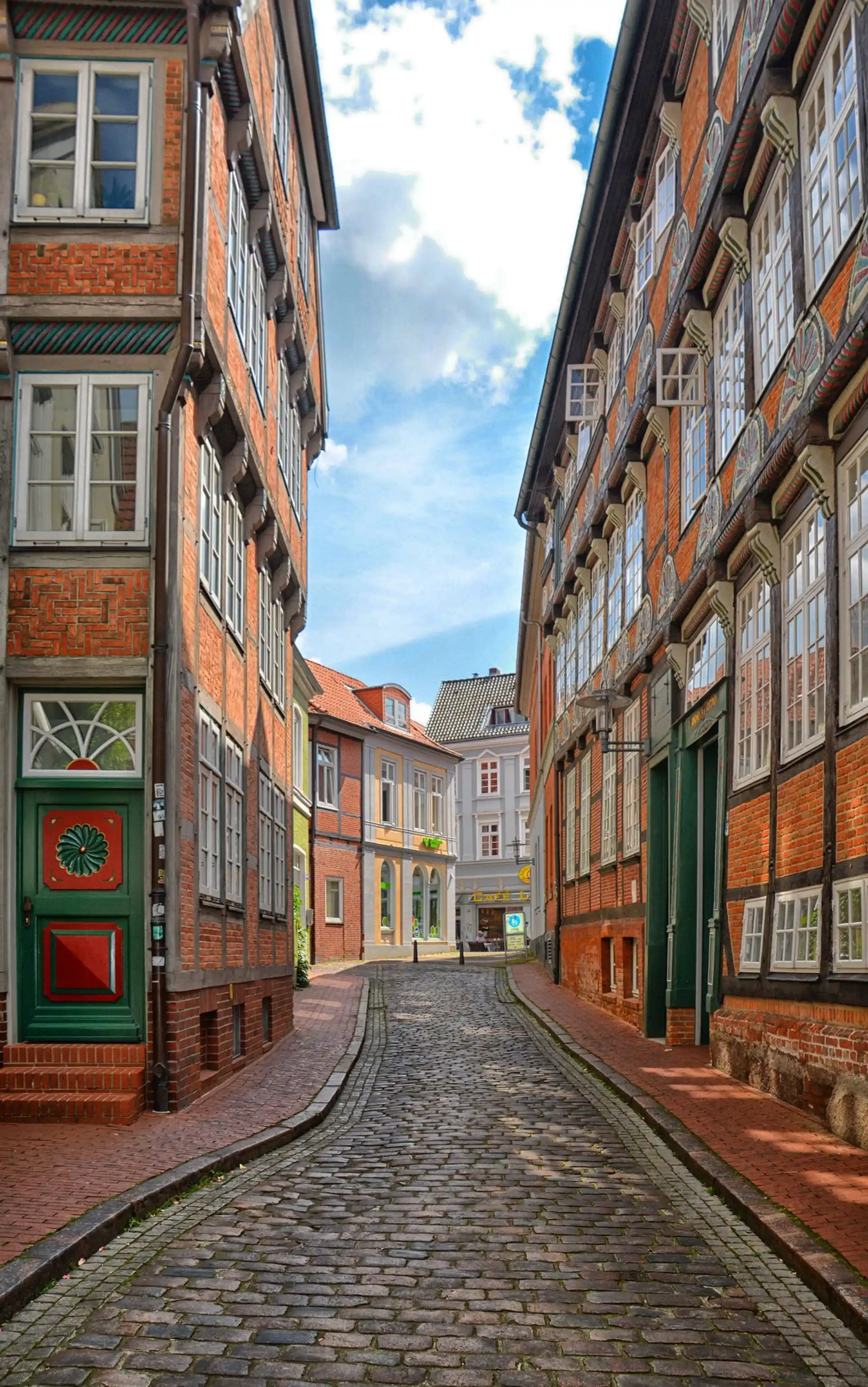 Schmale Kopfsteinpflasterstraße mit historischen Backsteinhäusern und vielen Fenstern.
