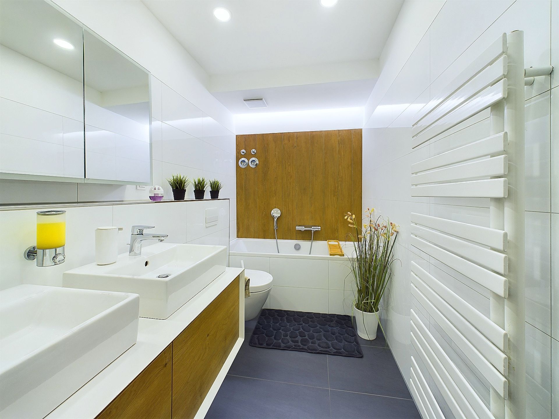 Modernes Badezimmer mit zwei Waschbecken, Badewanne, Spiegel und Handtuchheizkörper.