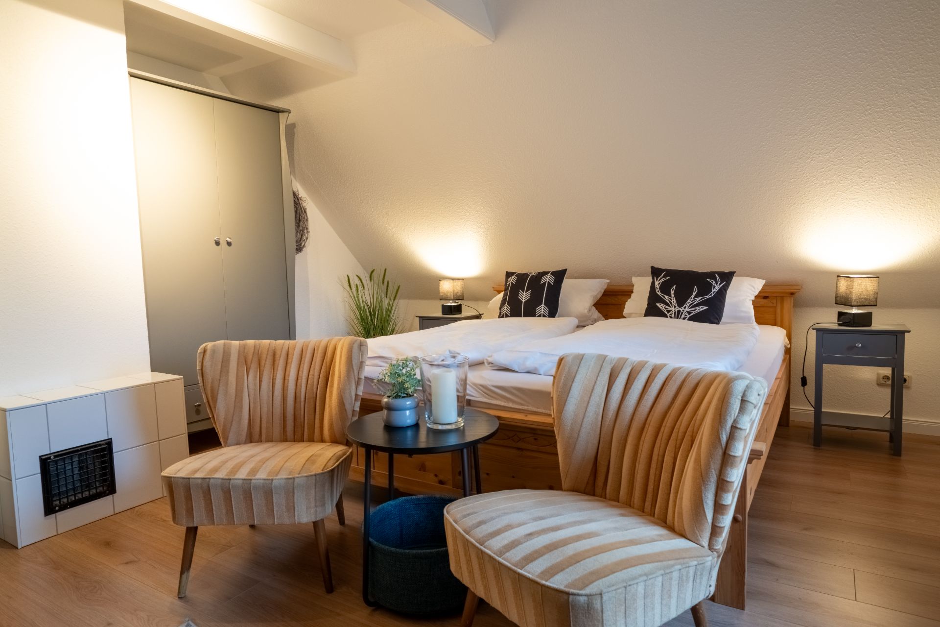 Gemütliches Schlafzimmer mit Doppelbett, zwei Sesseln, kleinem Tisch und Nachttischen unter Dachschräge.