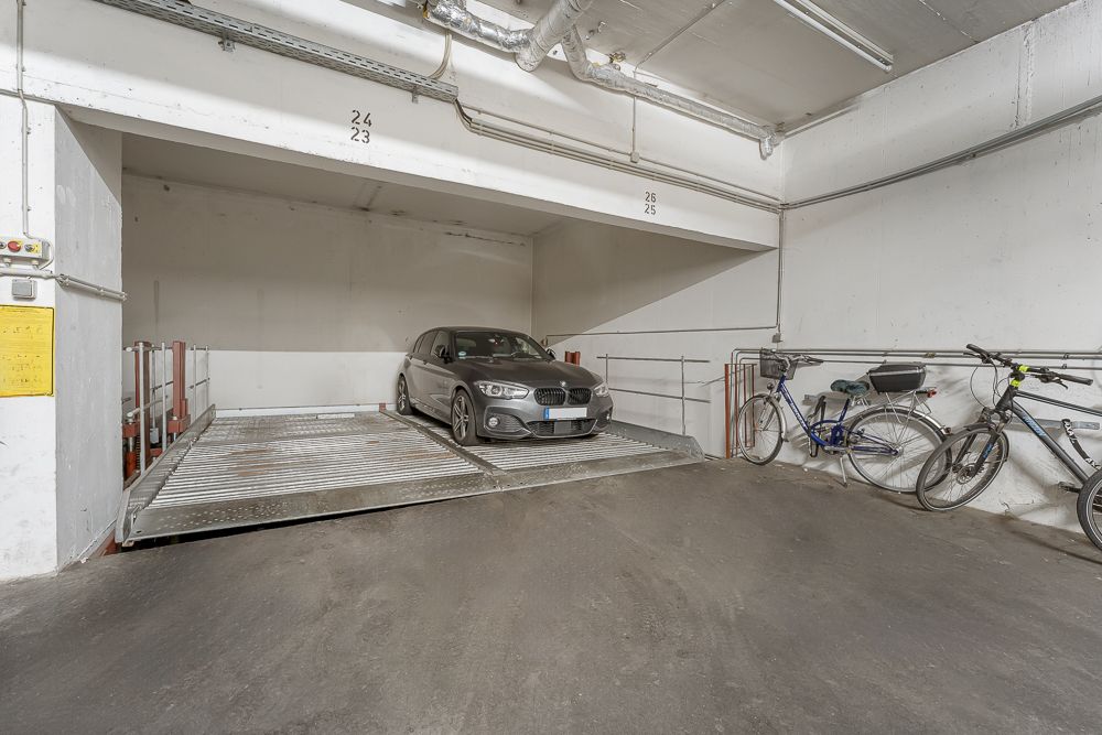 Auto steht auf einem Parksystem in einer Tiefgarage, daneben zwei abgestellte Fahrräder.